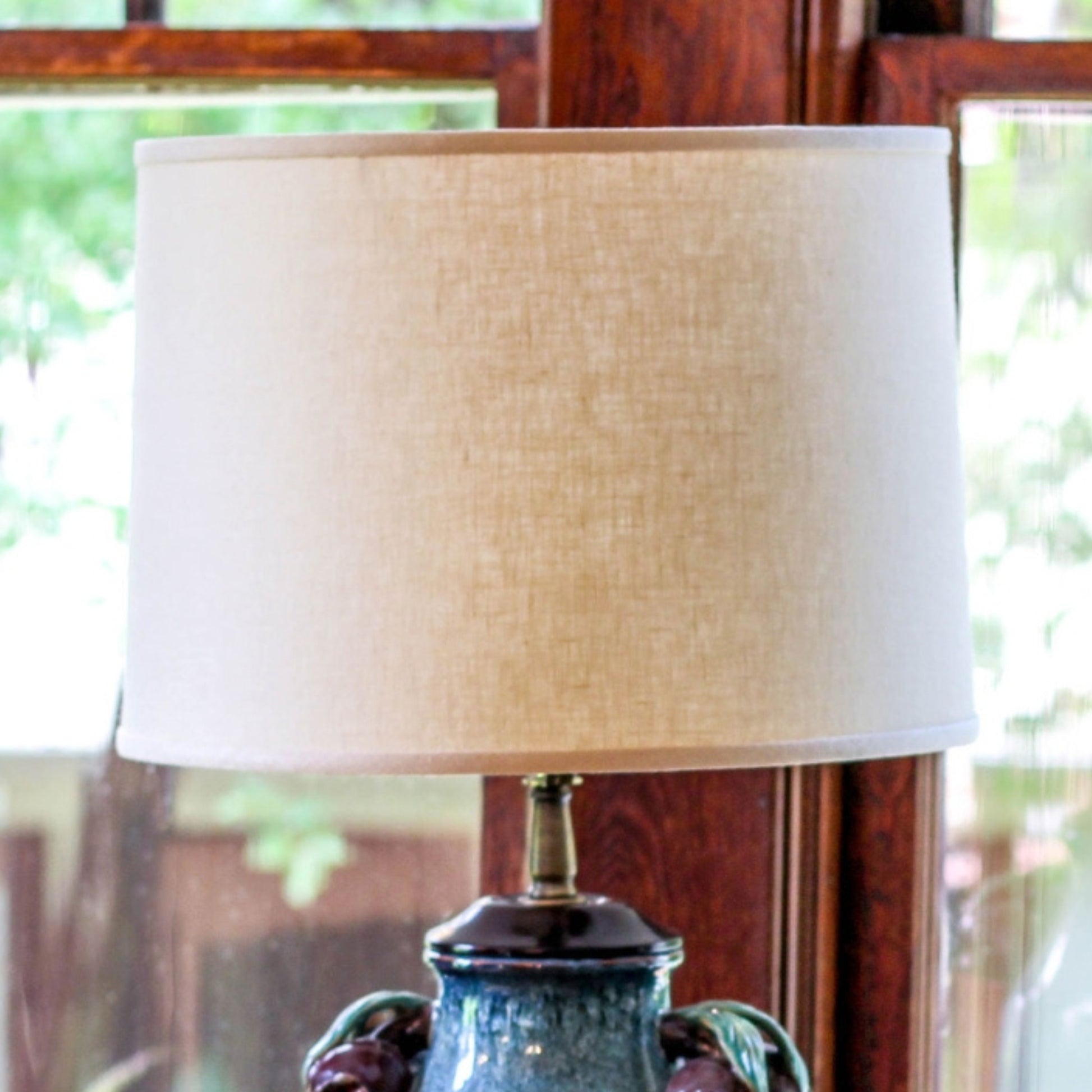 Cream linen drum lampshade on a decorative ceramic base