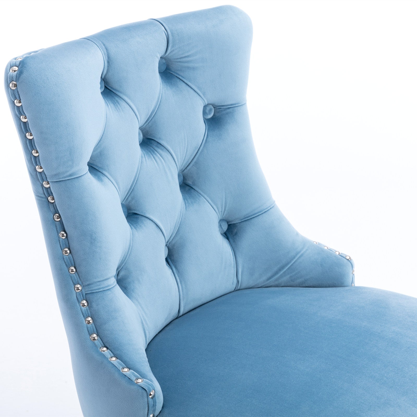 Closeup of a sky blue velvet armchair with tufted back and silver nailhead trim accents