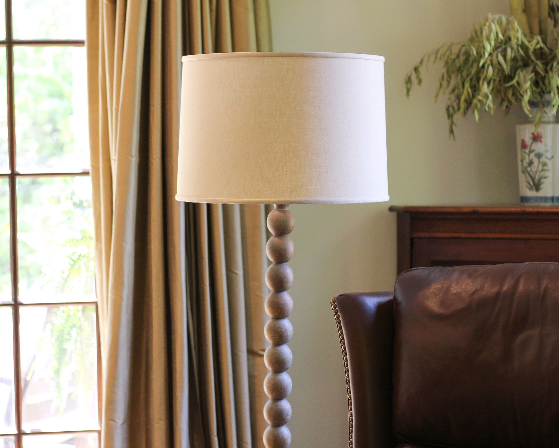 Beige drum lampshade on a wooden beaded floor lamp