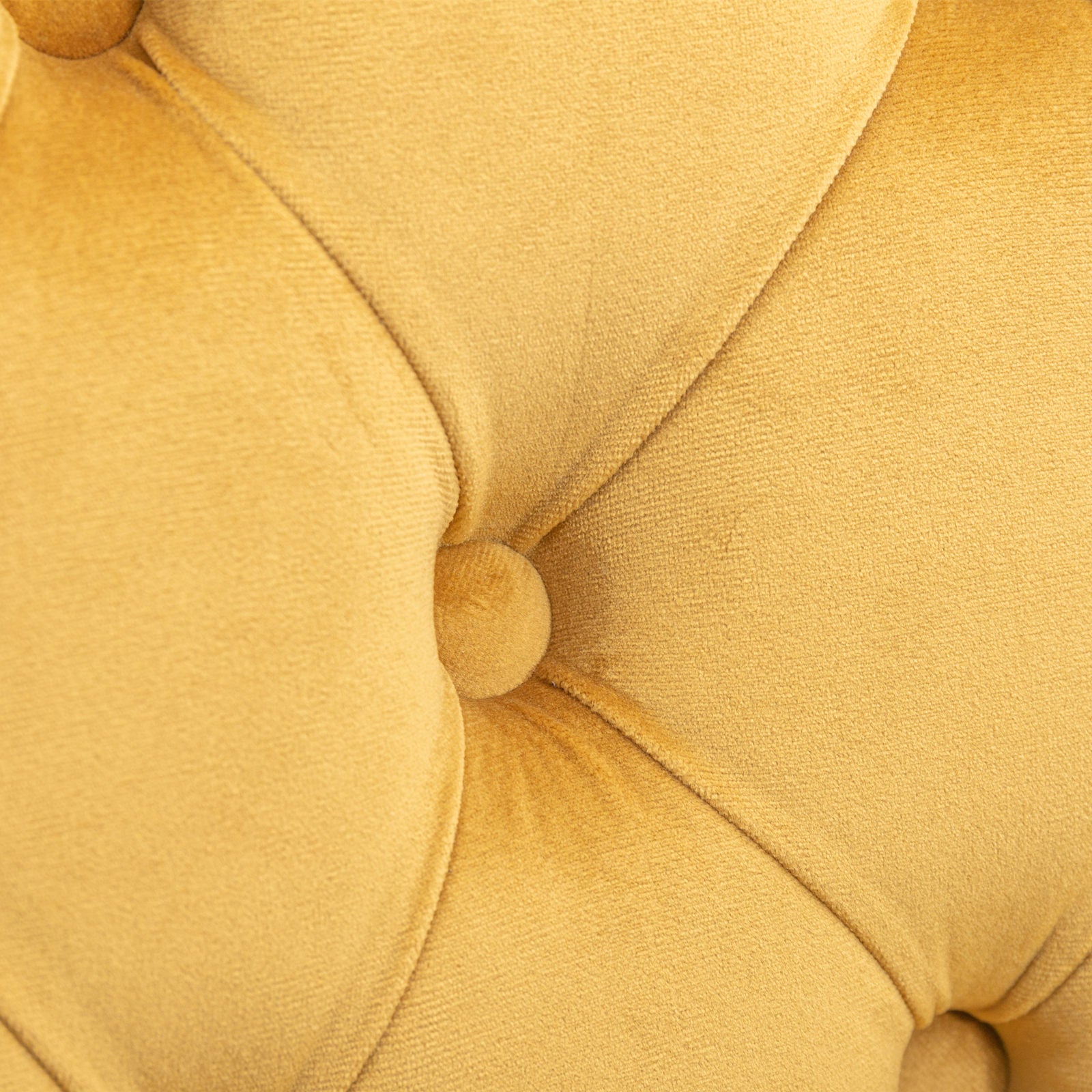 Closeup of yellow velvet tufted sofa detail showing button and stitching