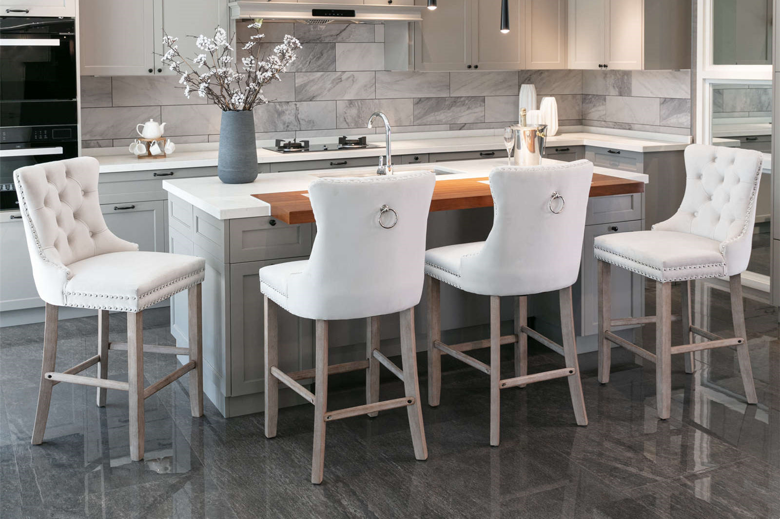 Elegant white tufted bar stools with silver nailhead trim around a kitchen island