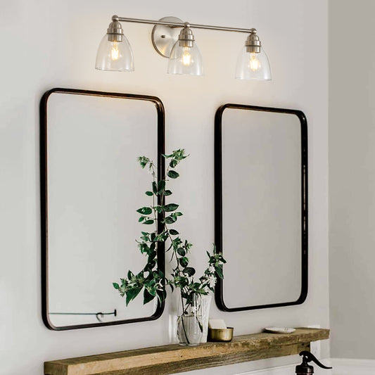 Brushed nickel vanity light with three clear glass shades above modern mirrors
