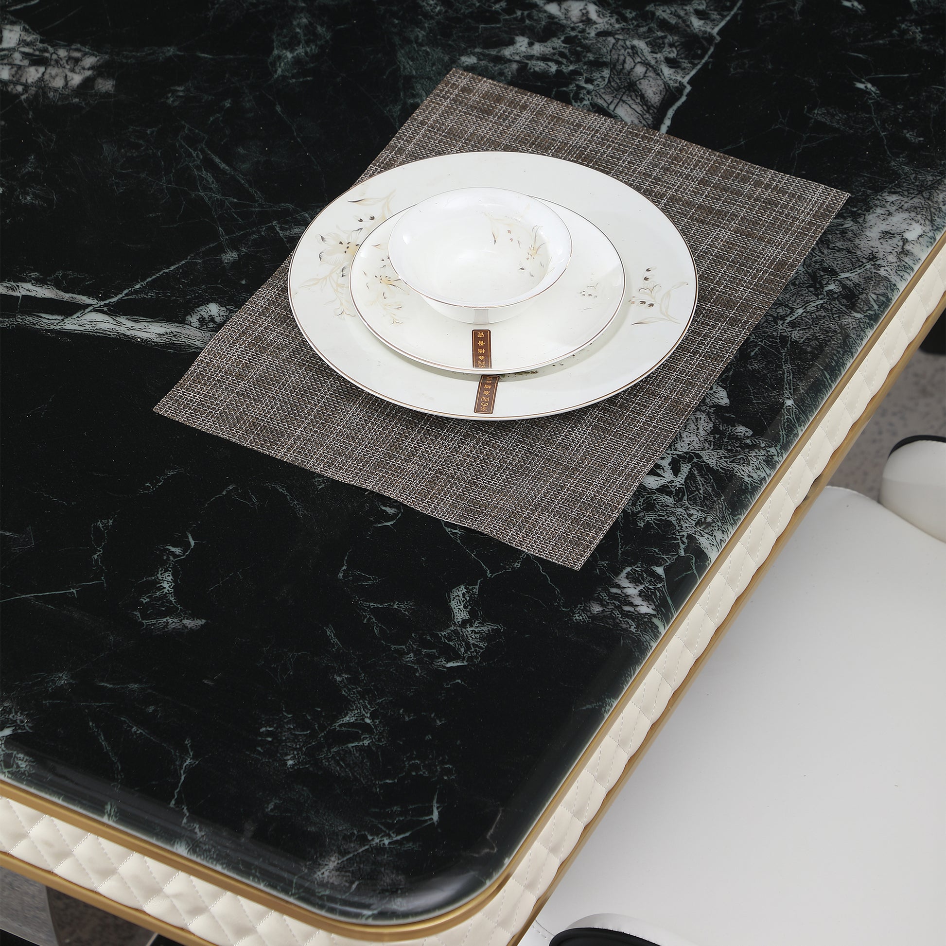 Elegant white porcelain dinner plate set with subtle floral design on dark marble tabletop