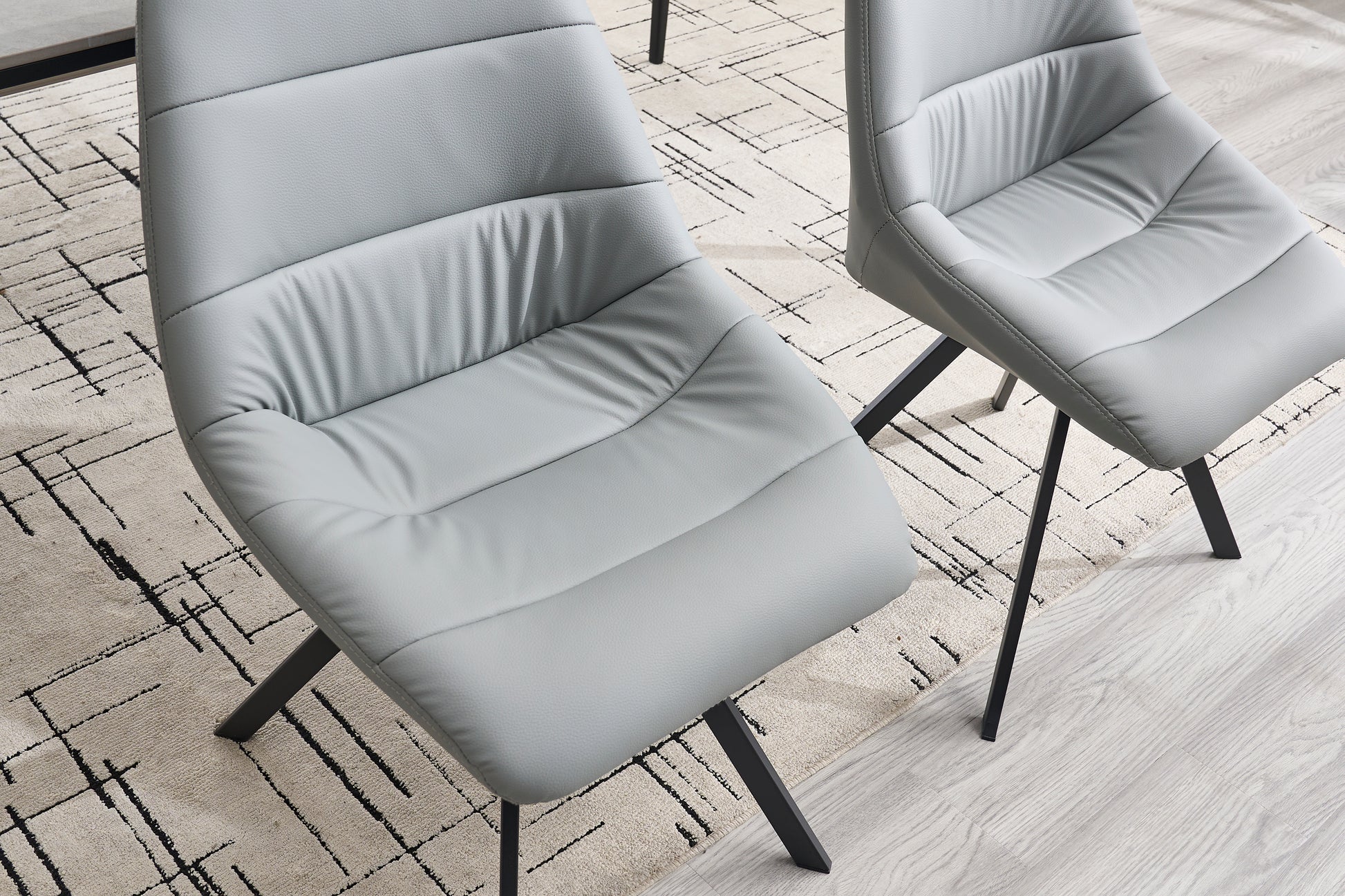 Light grey faux leather dining chair with channel tufting and black metal legs