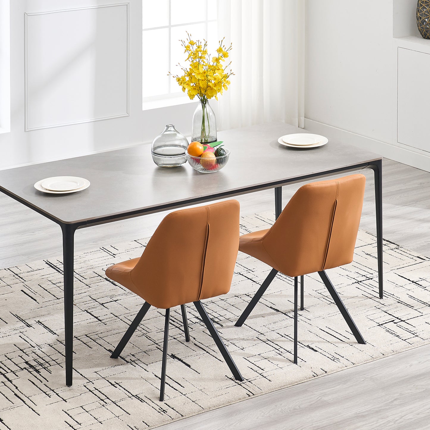 Two modern tan leather dining chairs with black metal legs