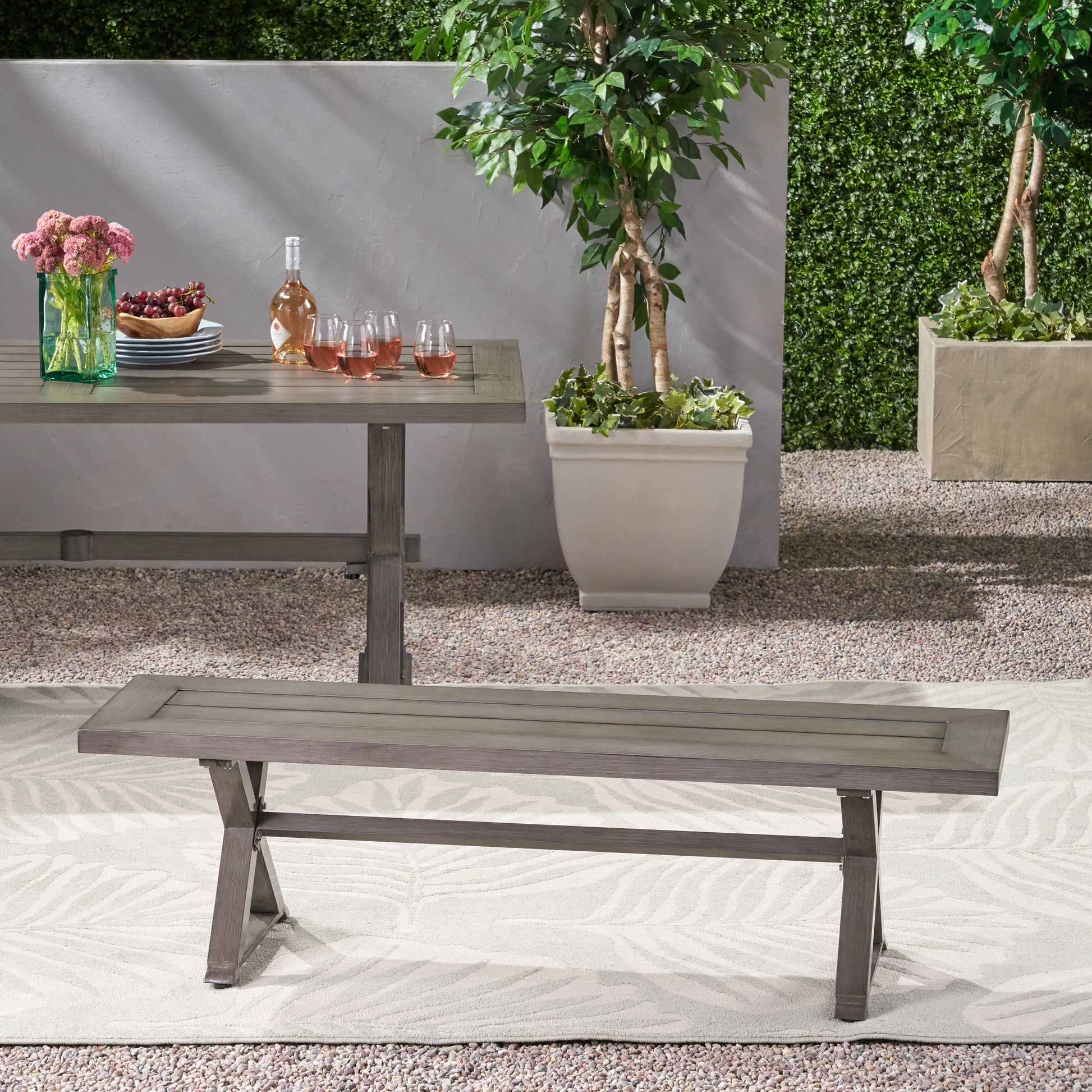 Grey wood dining bench with crossleg base on patio rug