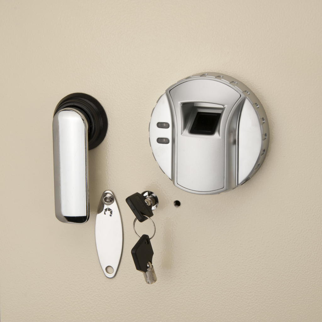Biometric fingerprint scanner with chrome handle and two keys on a beige safe