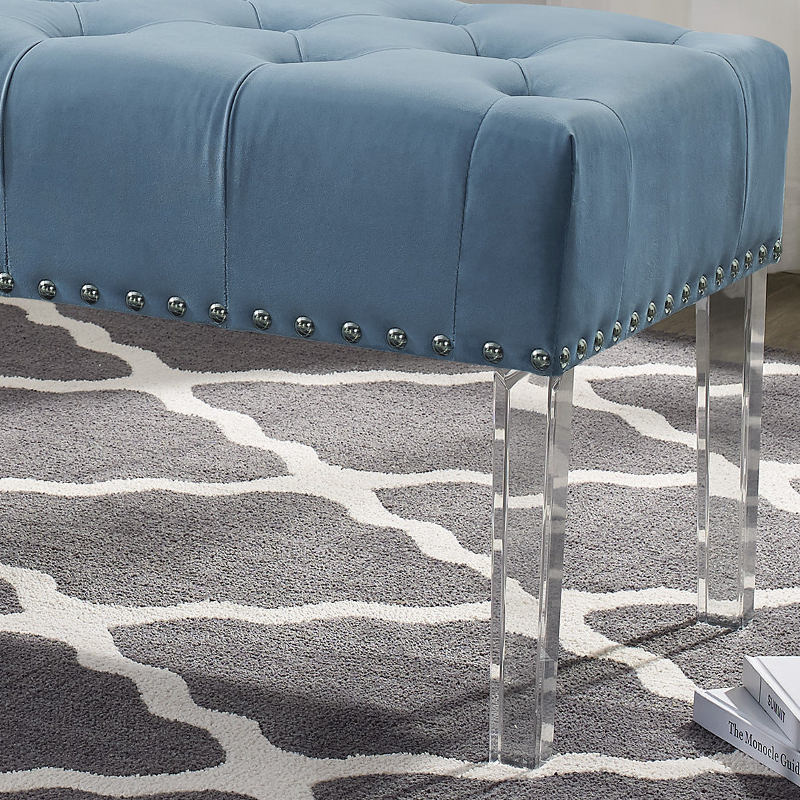 Blue velvet ottoman with button tufting and silver nailhead trim accents