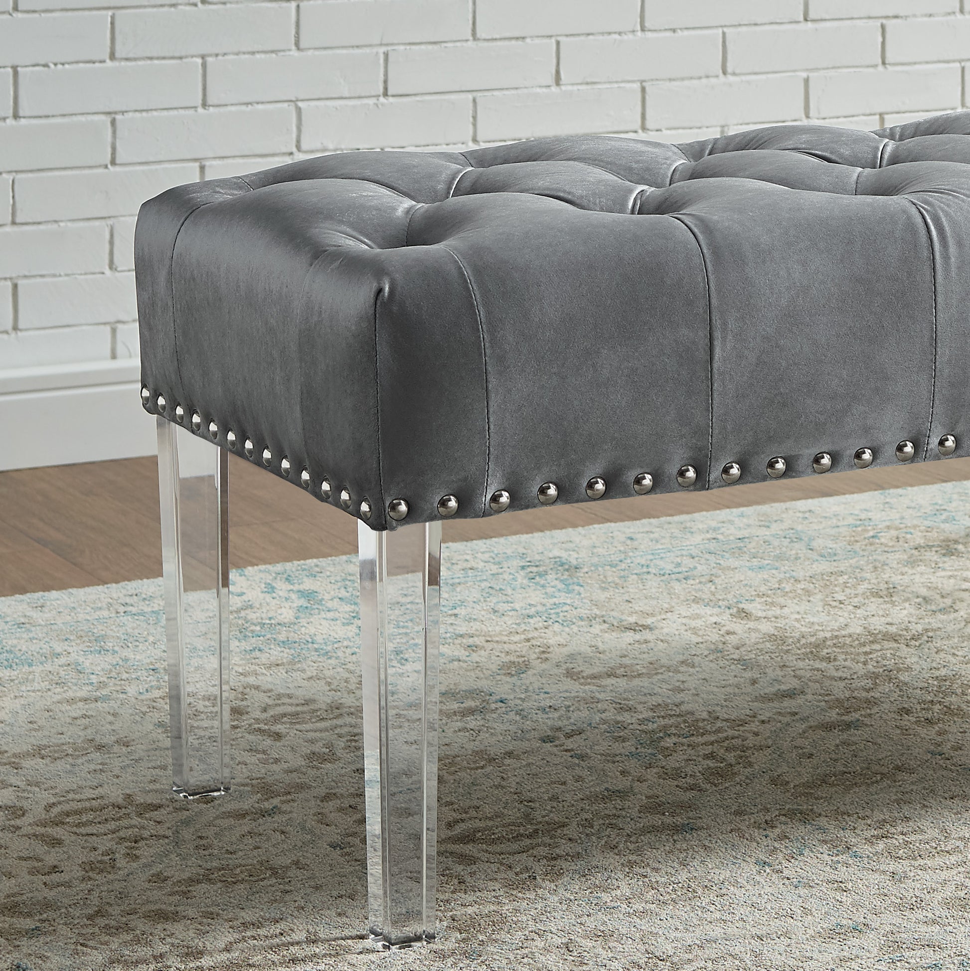 Tufted grey leather ottoman with silver nailhead trim and clear acrylic legs