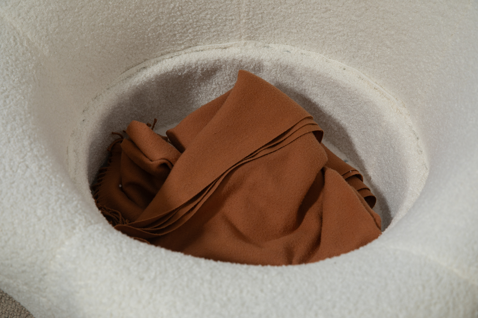 Brown woven scarf folded inside a cream boucle textured bucket hat