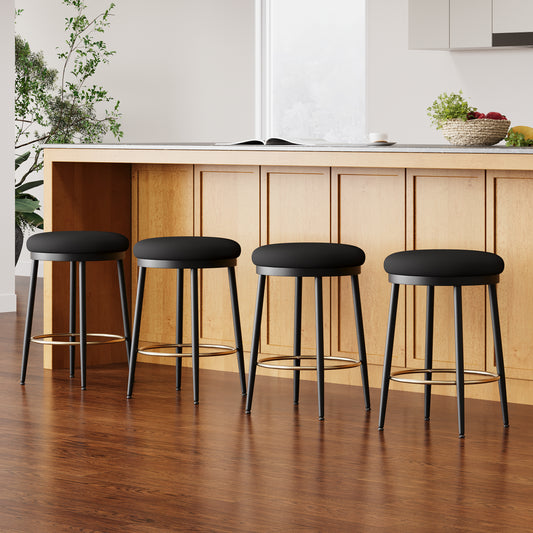 Four black upholstered bar stools with gold footrests arranged by a wooden kitchen island