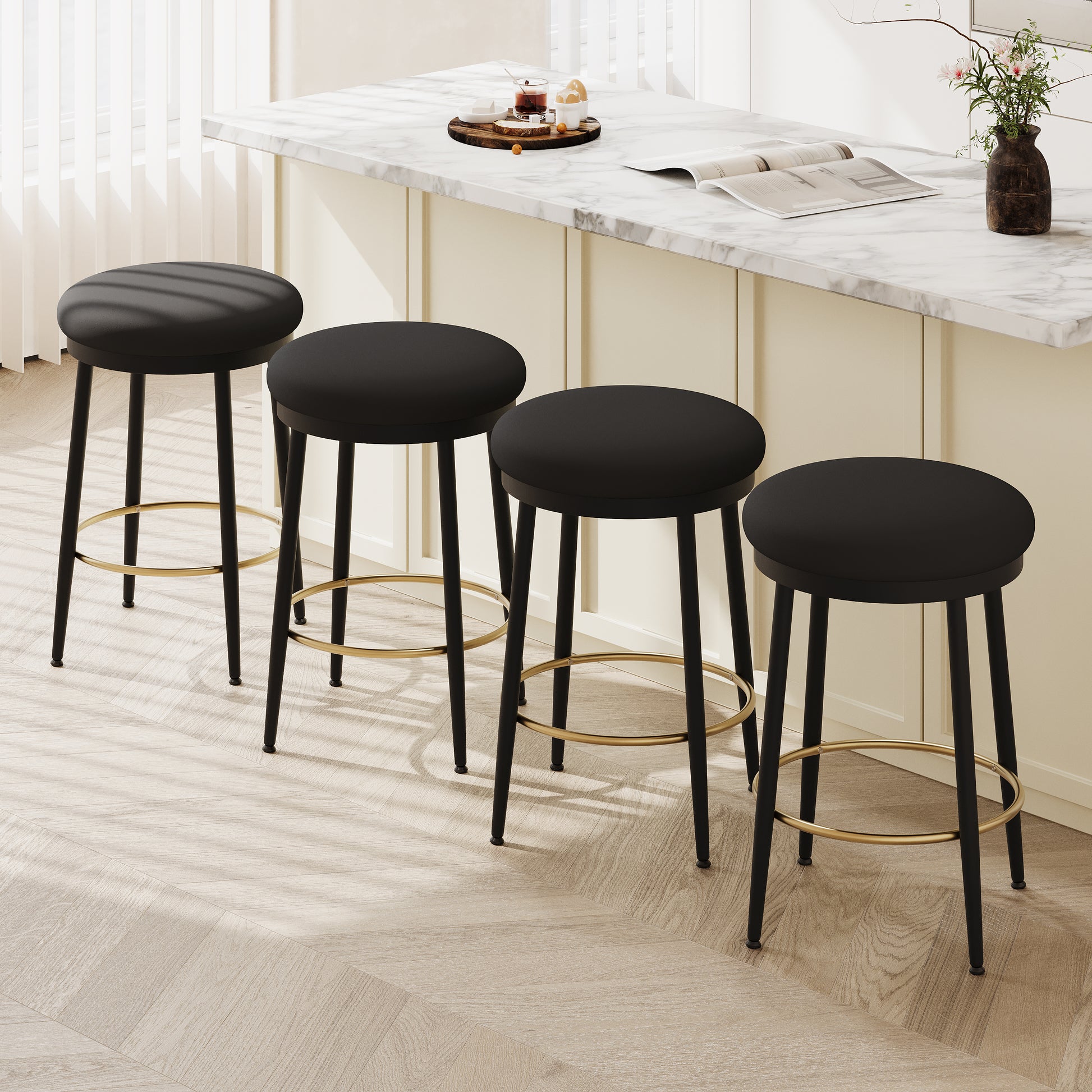 Four black upholstered bar stools with gold footrests arranged by a marble kitchen island