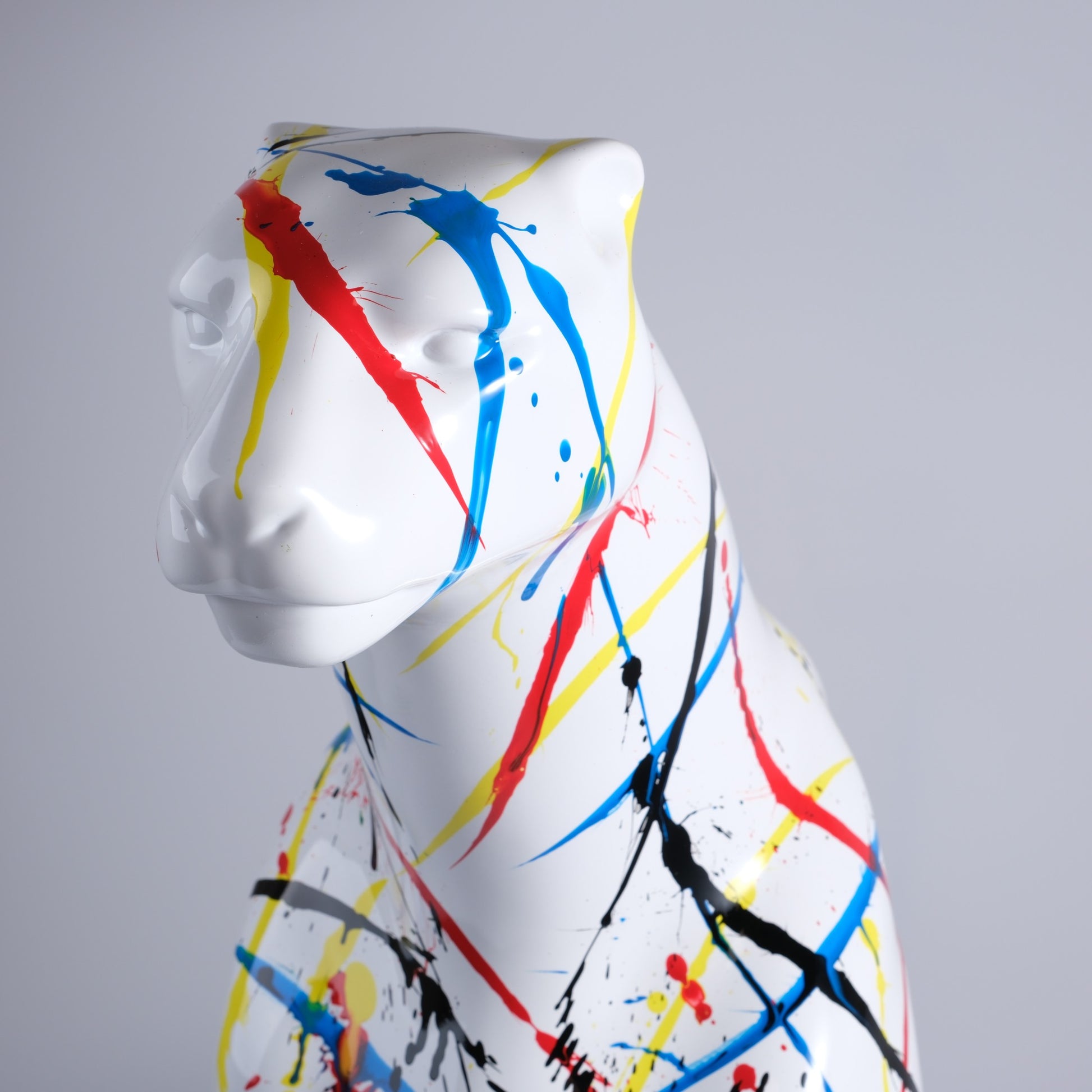 White panther statue with abstract red blue and yellow paint splatters modern art decor