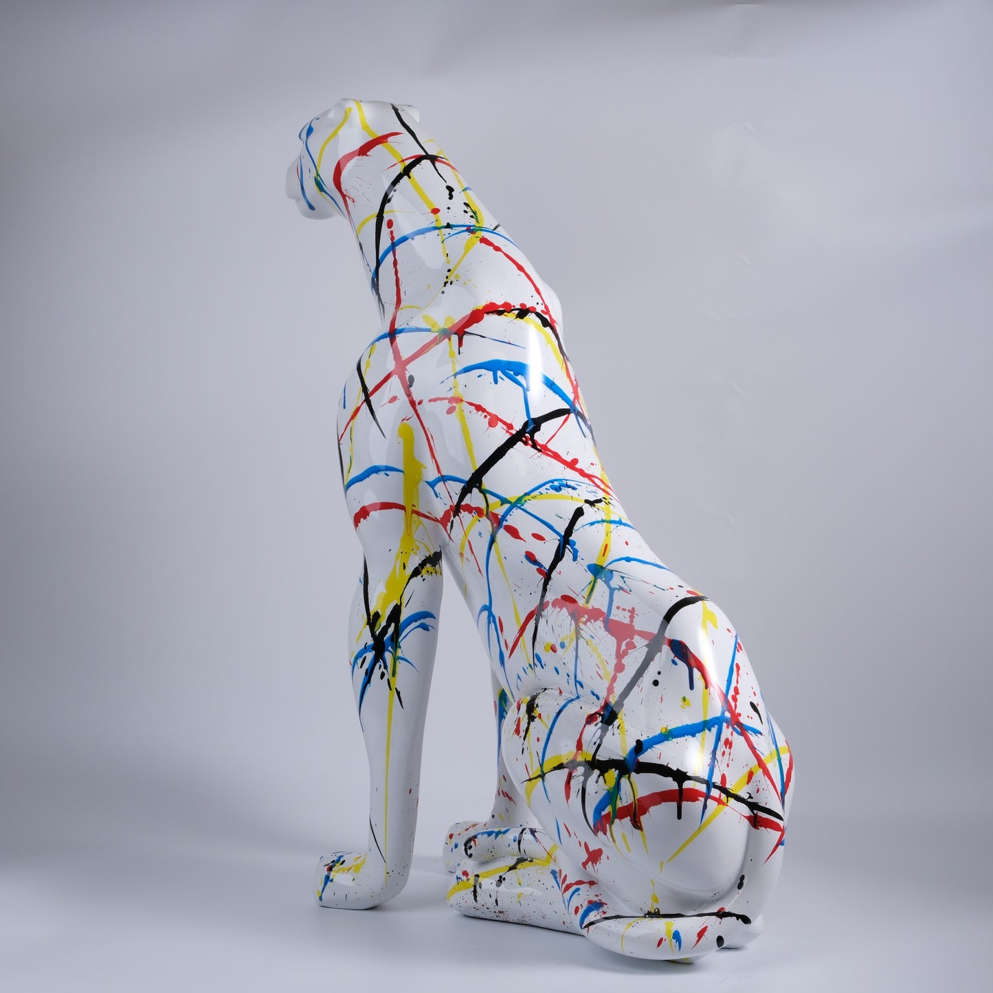 White ceramic cheetah statue with colorful paint splatters