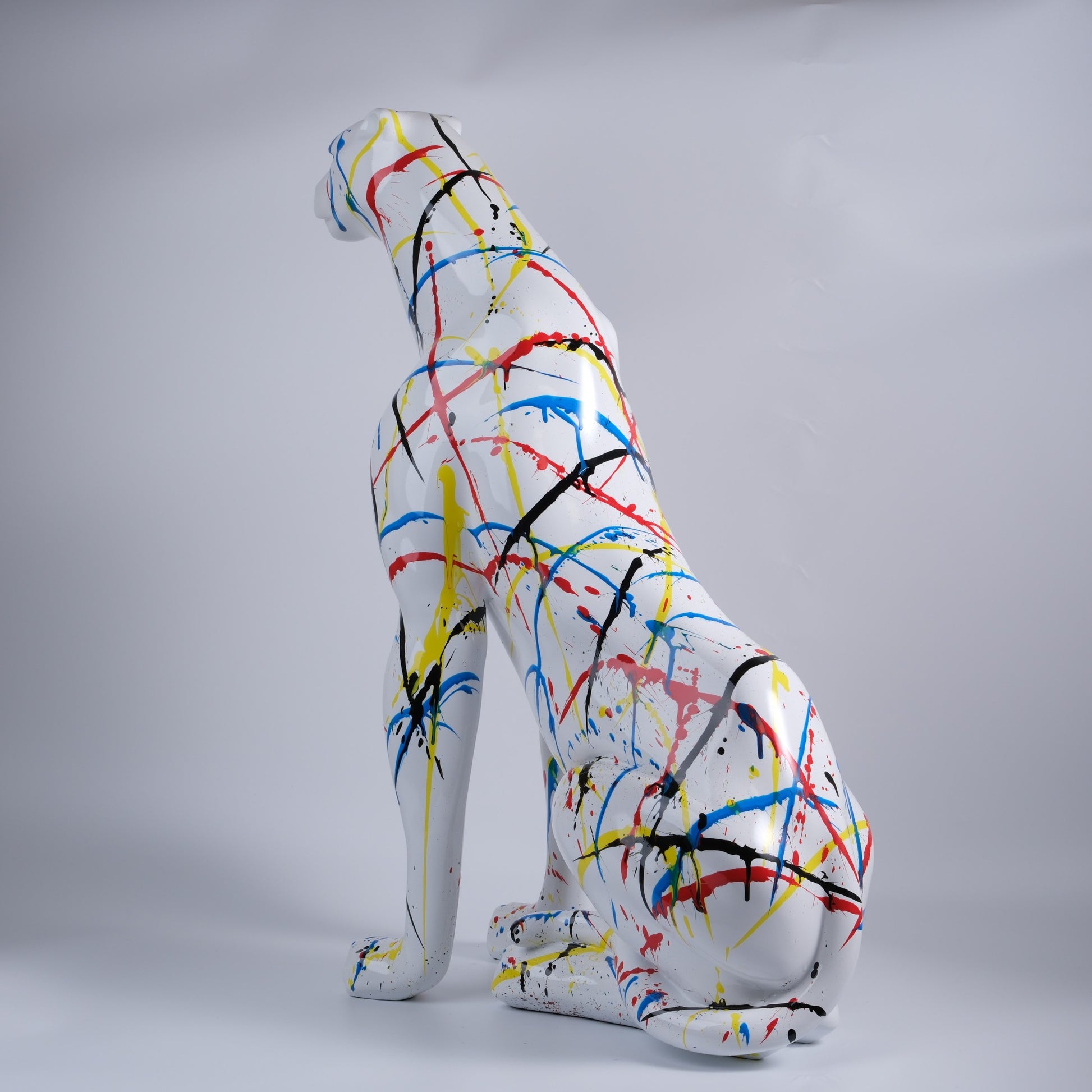 White ceramic cheetah statue with colorful paint splatters