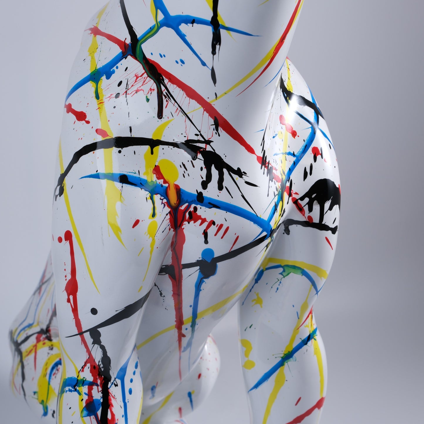 White abstract sculpture with splattered red blue yellow and black paint