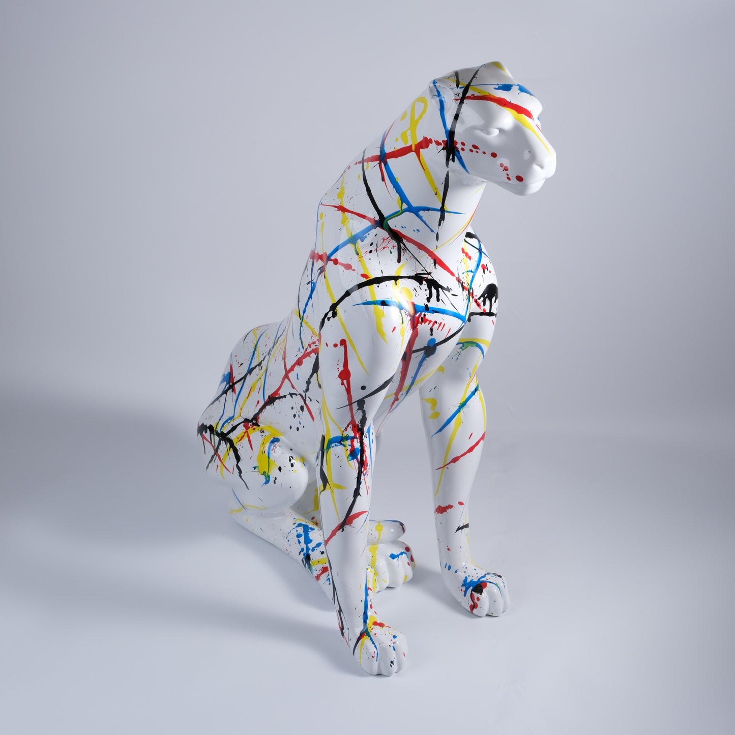 White leopard statue with vibrant splatter paint design and colorful abstract art accents