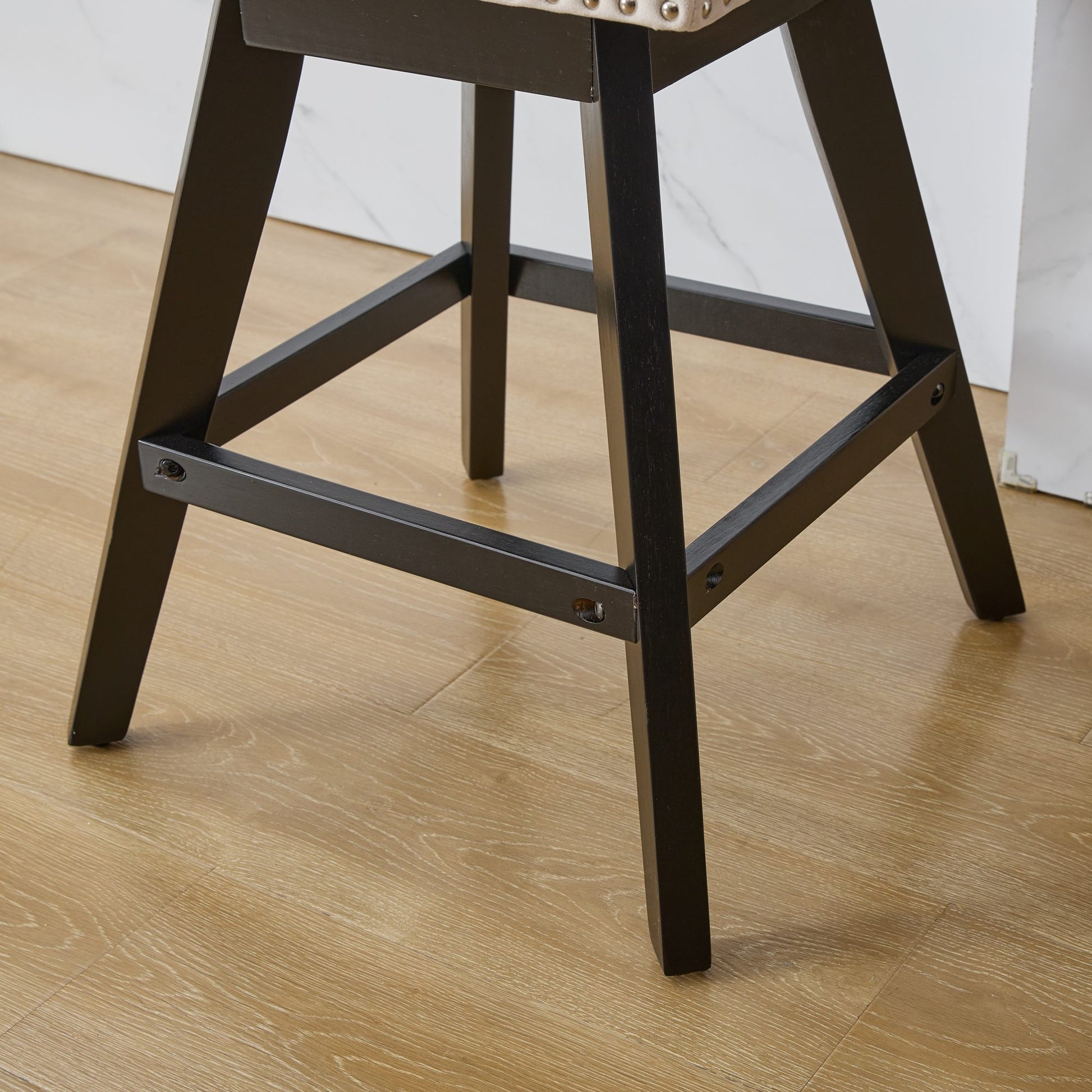 Dark brown wooden bar stool legs with stretcher bars and upholstered seat detail