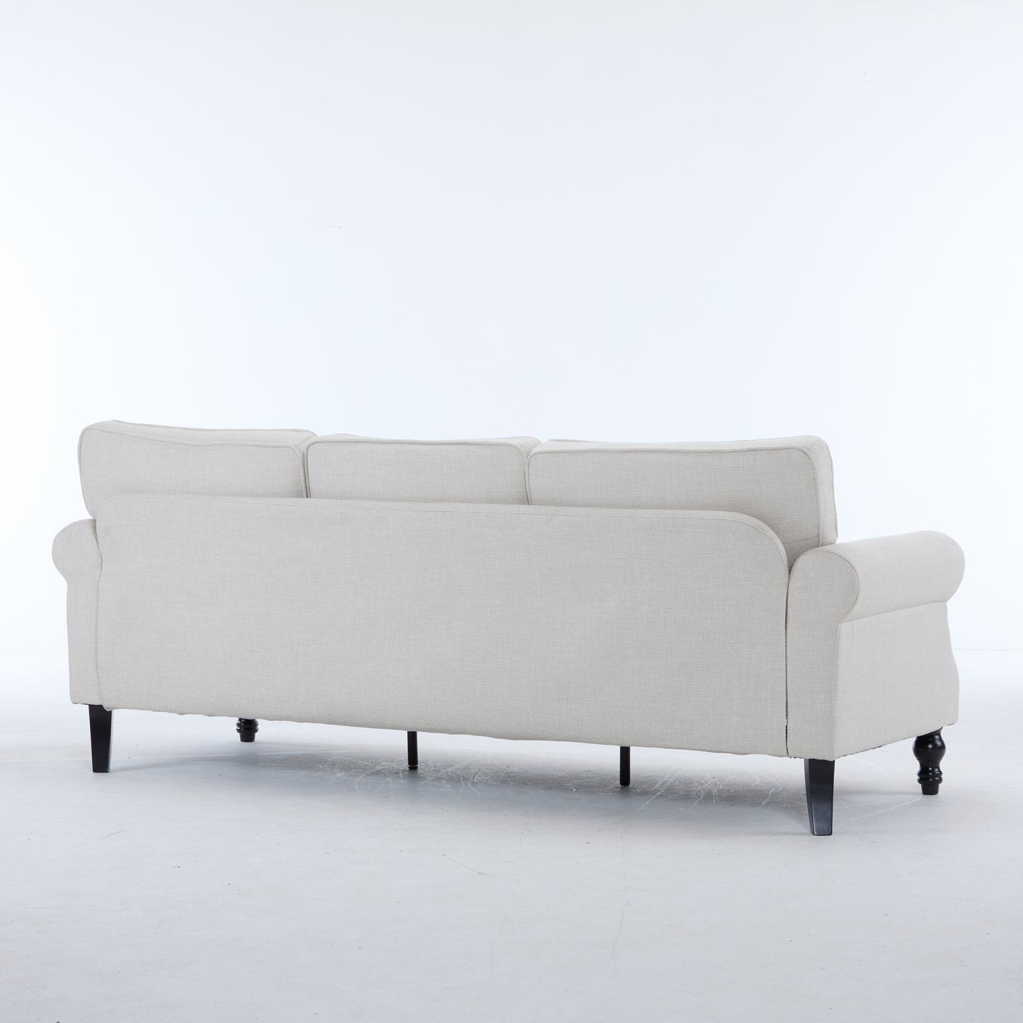 Rear view of a light beige fabric seater sofa with rolled arms and dark wooden legs