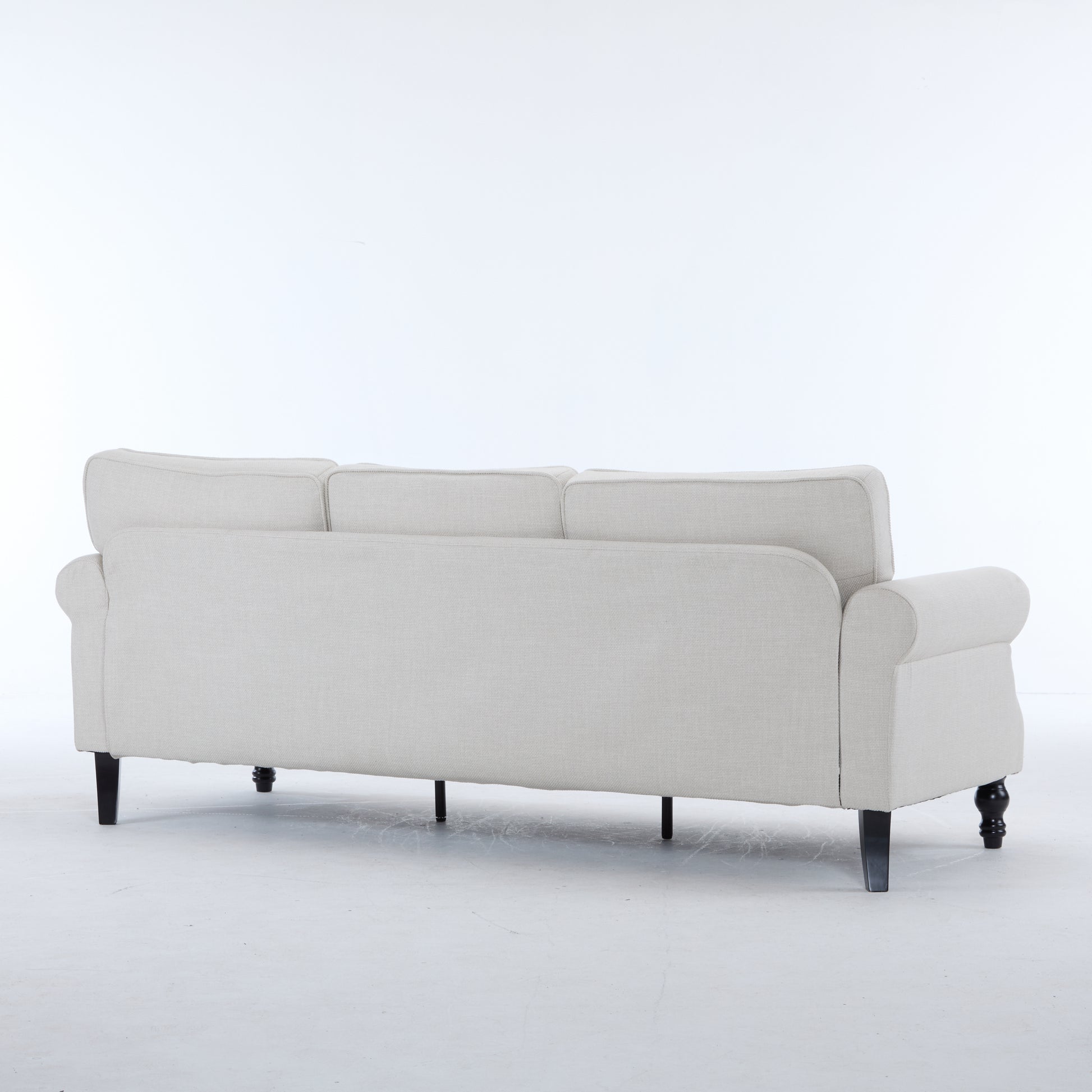 Rear view of a light beige fabric seater sofa with rolled arms and dark wooden legs