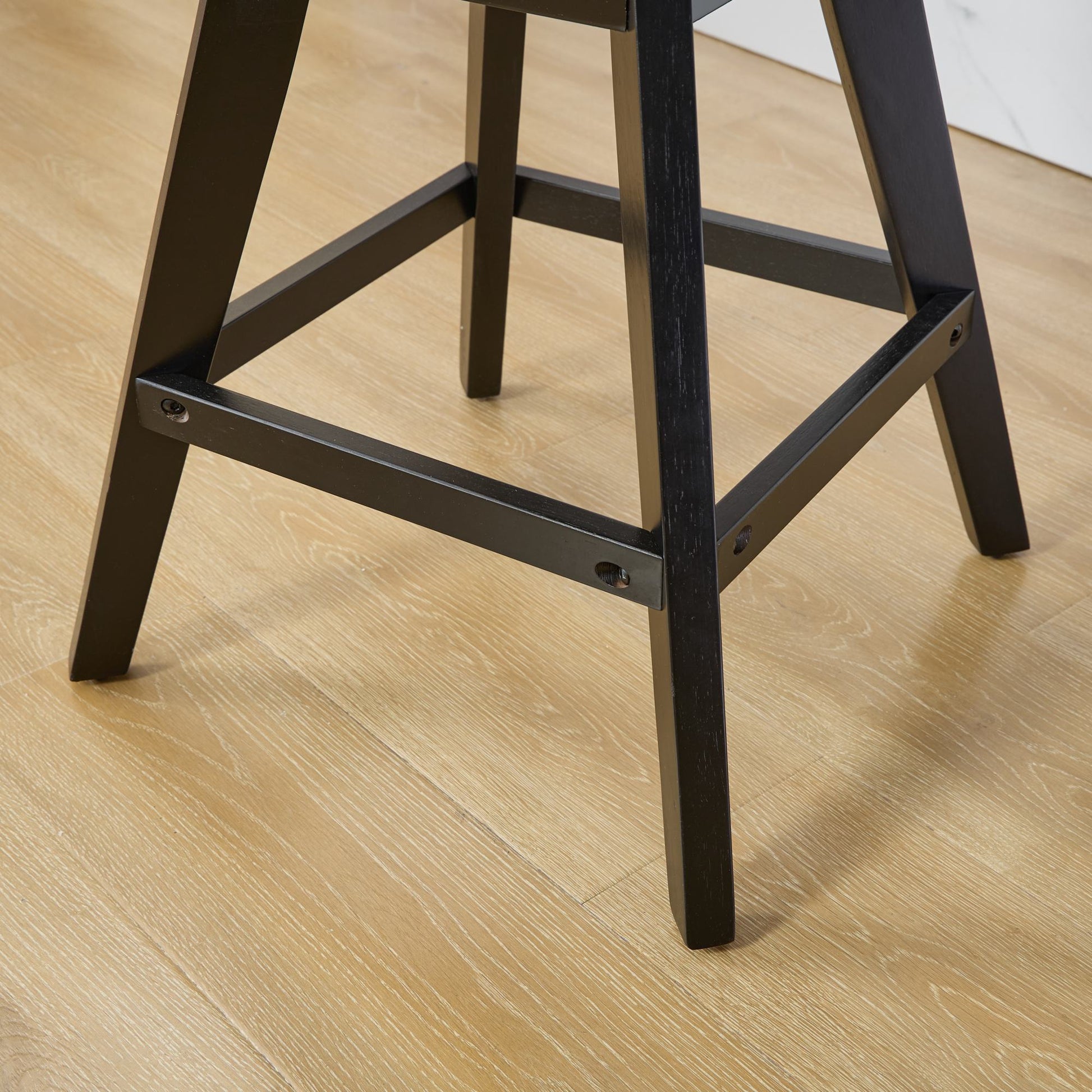 Black wooden bar stool legs on a light wood floor