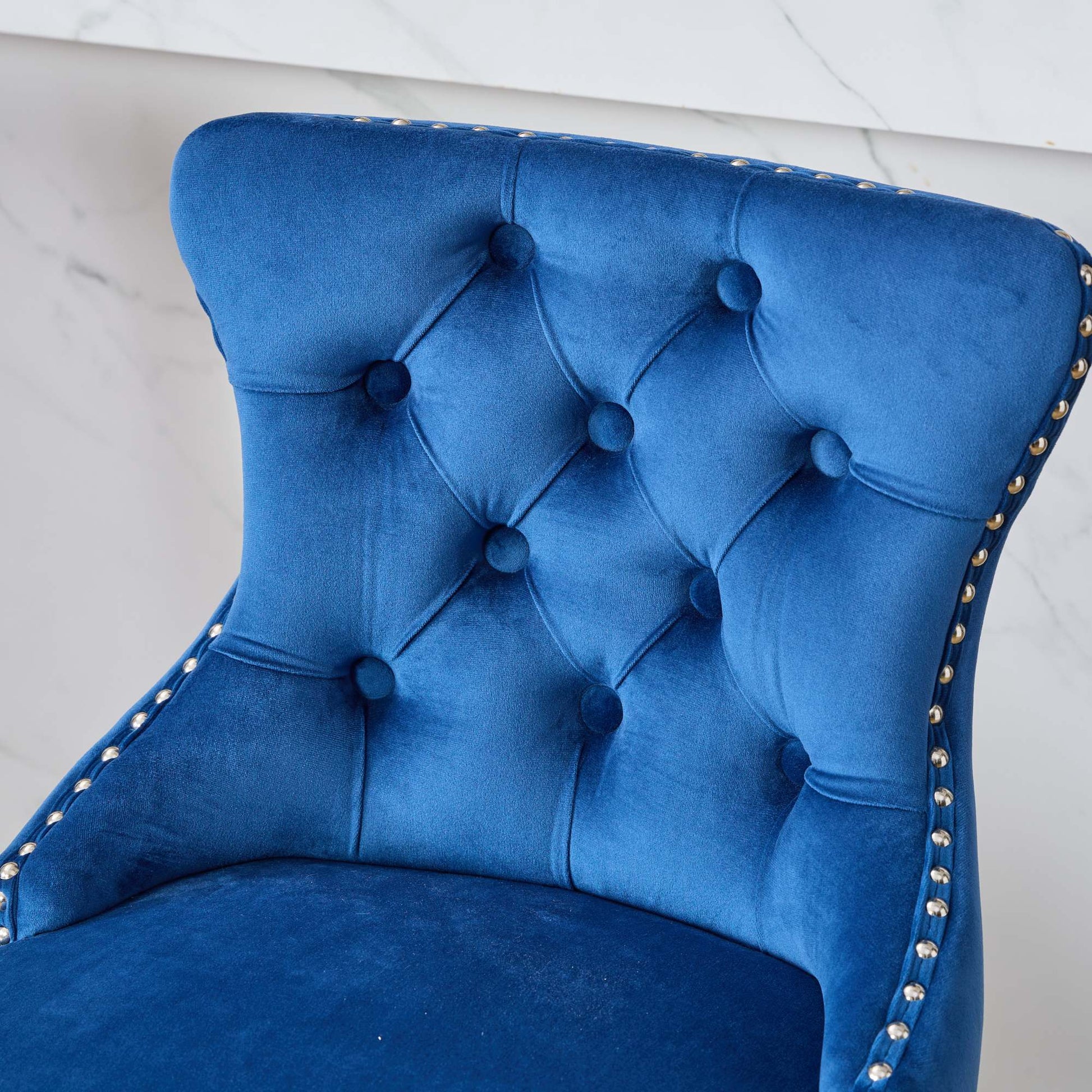 Deep blue velvet tufted accent chair with polished brass nailhead trim