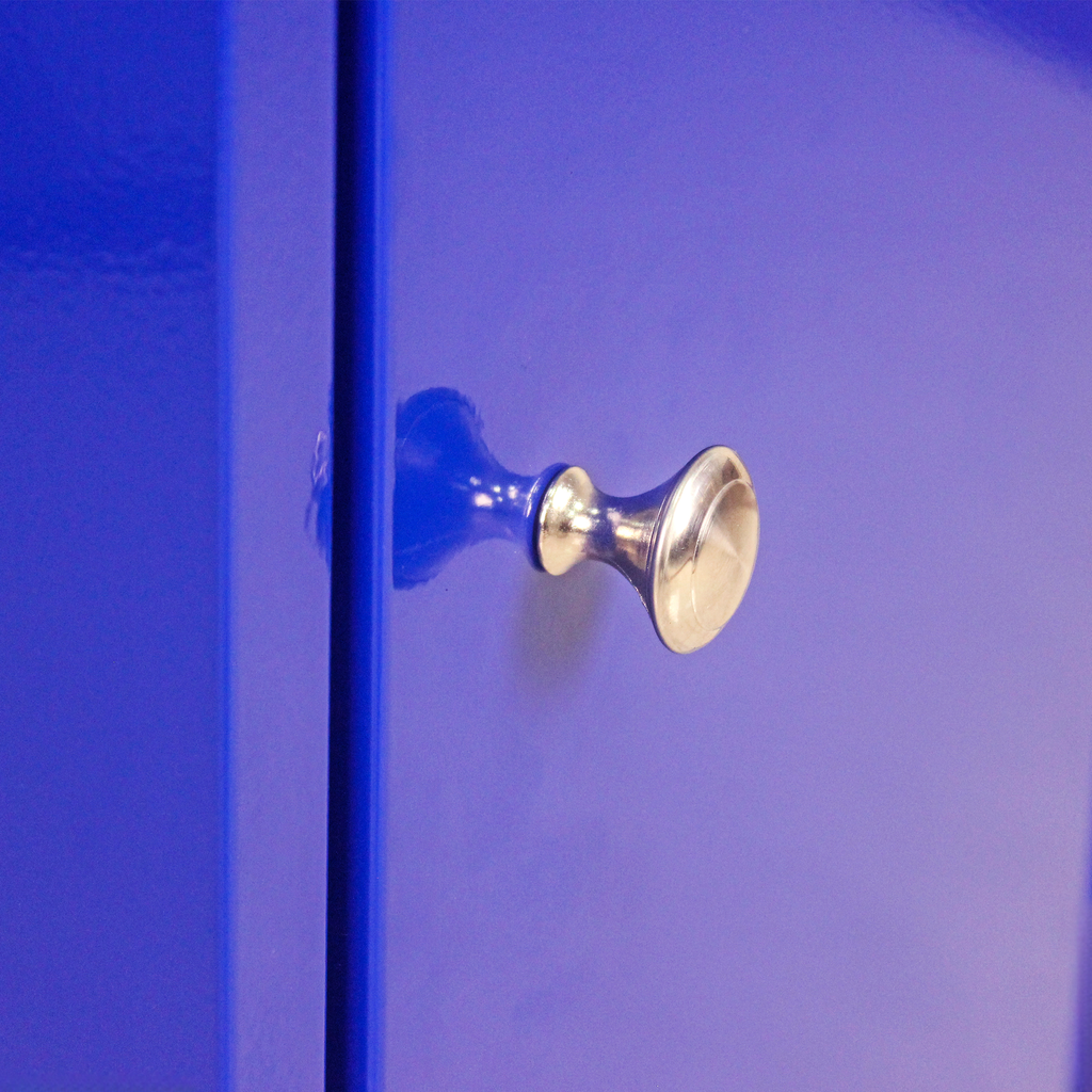 Polished silver knob on a vibrant blue cabinet door