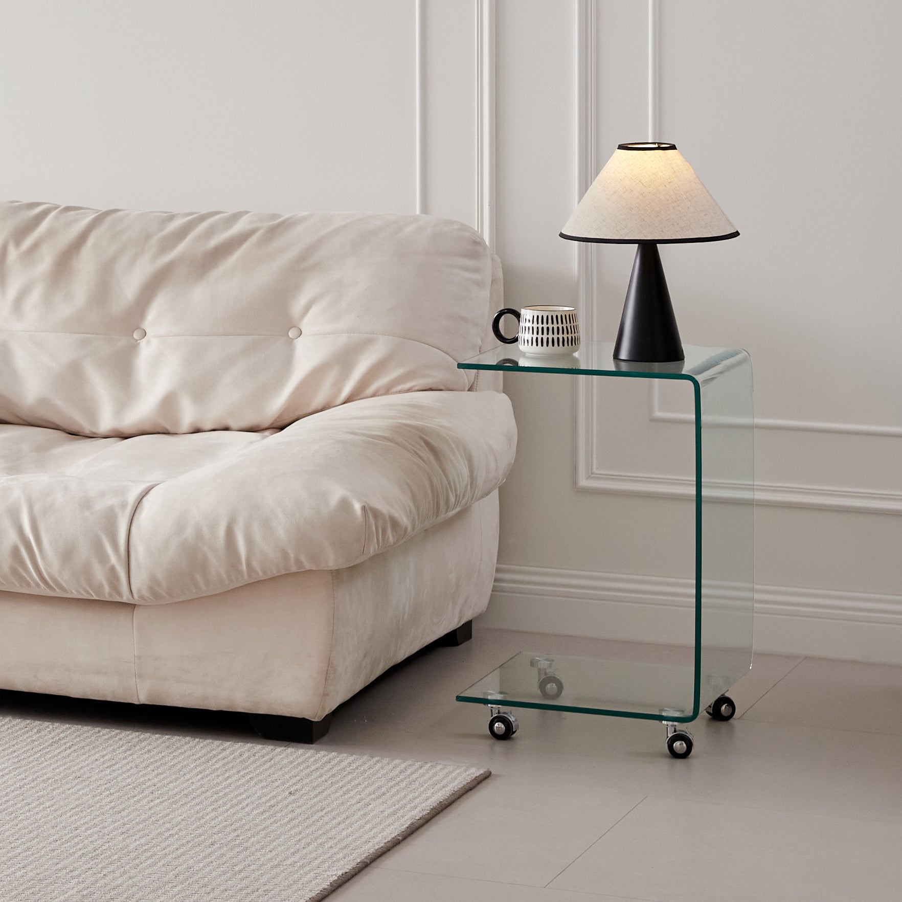 Cream tufted sofa next to a modern clear acrylic Ctable with wheels