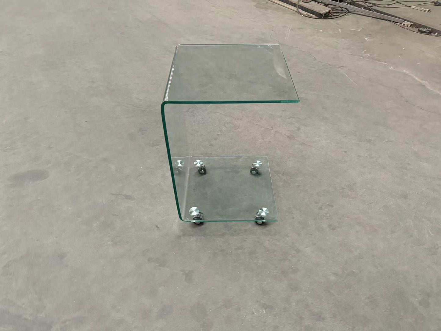 Curved clear glass side table with a lower shelf and silver casters