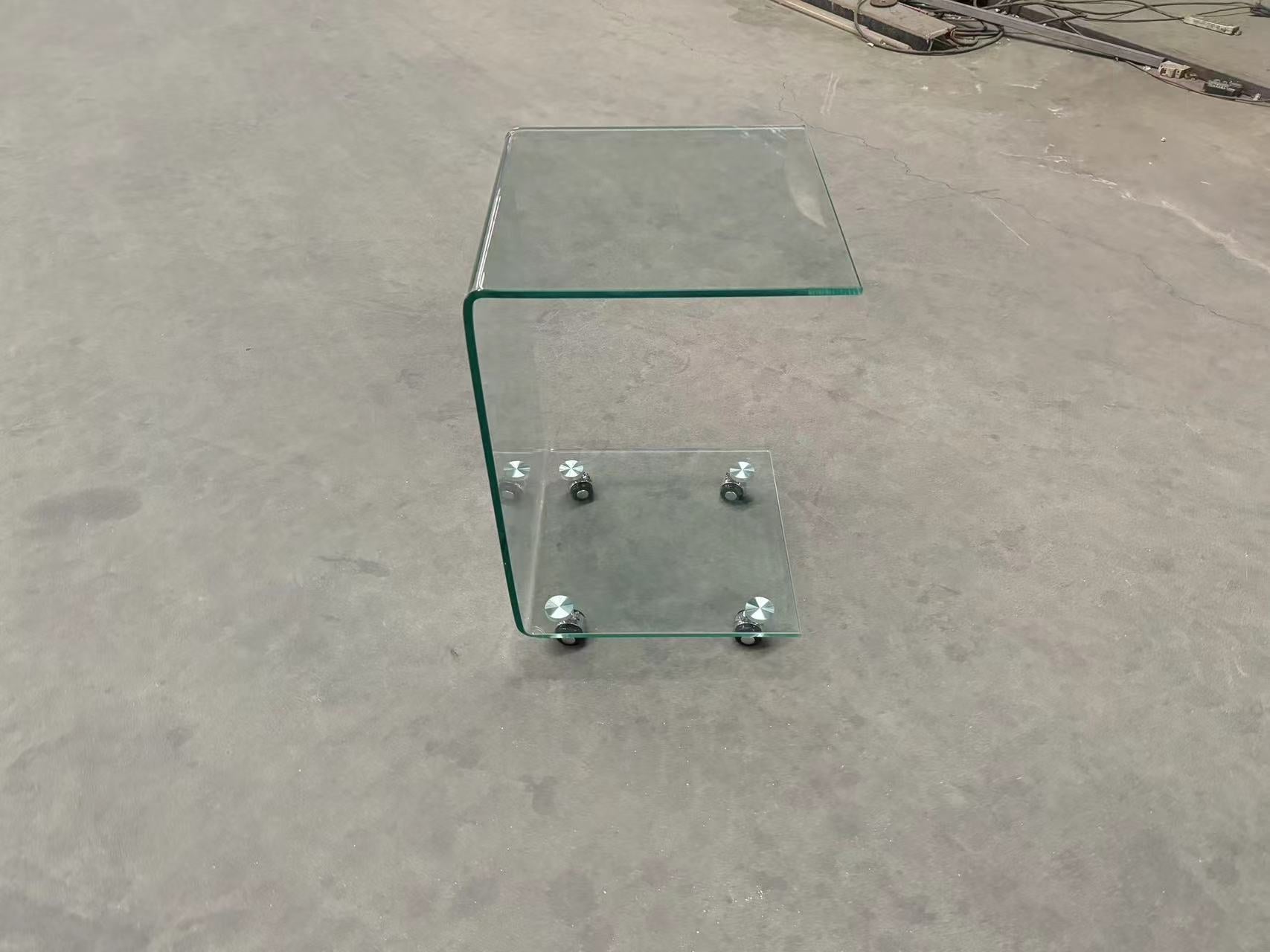Curved clear glass side table with a lower shelf and silver casters