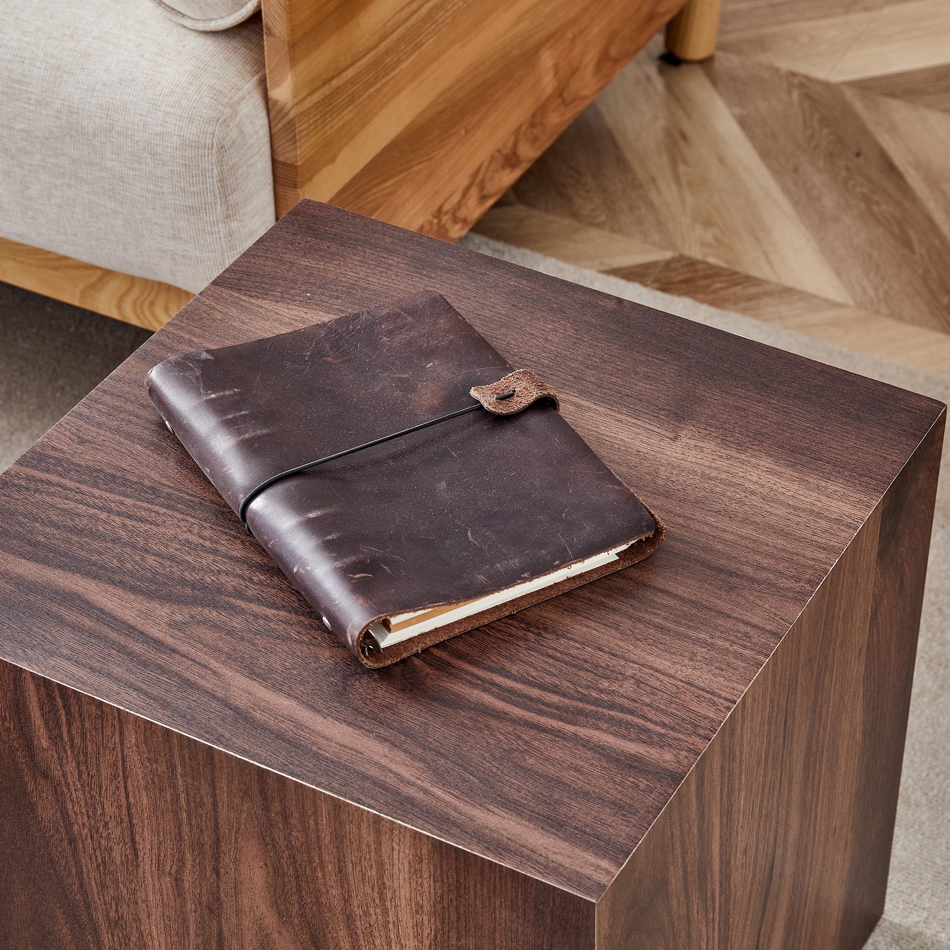 Brown distressed leather journal with elastic closure on dark wood side table