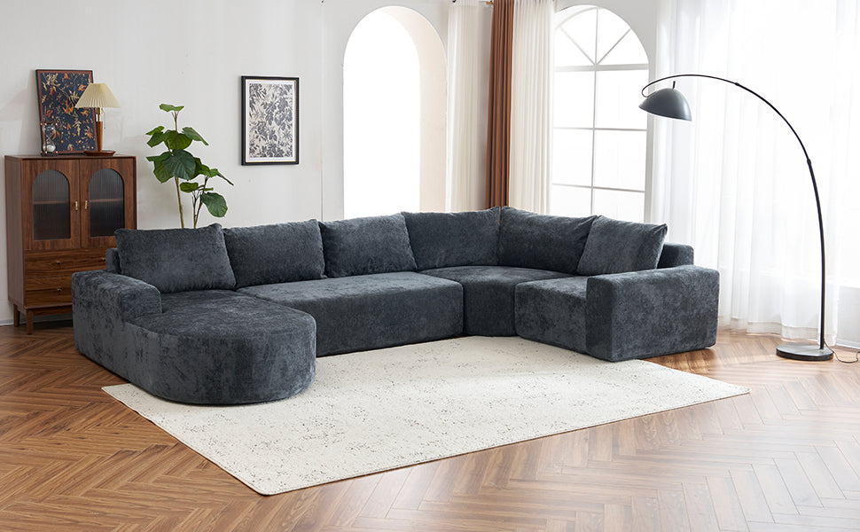 Dark grey plush Ushaped sectional sofa with rounded chaise lounge on a cream rug