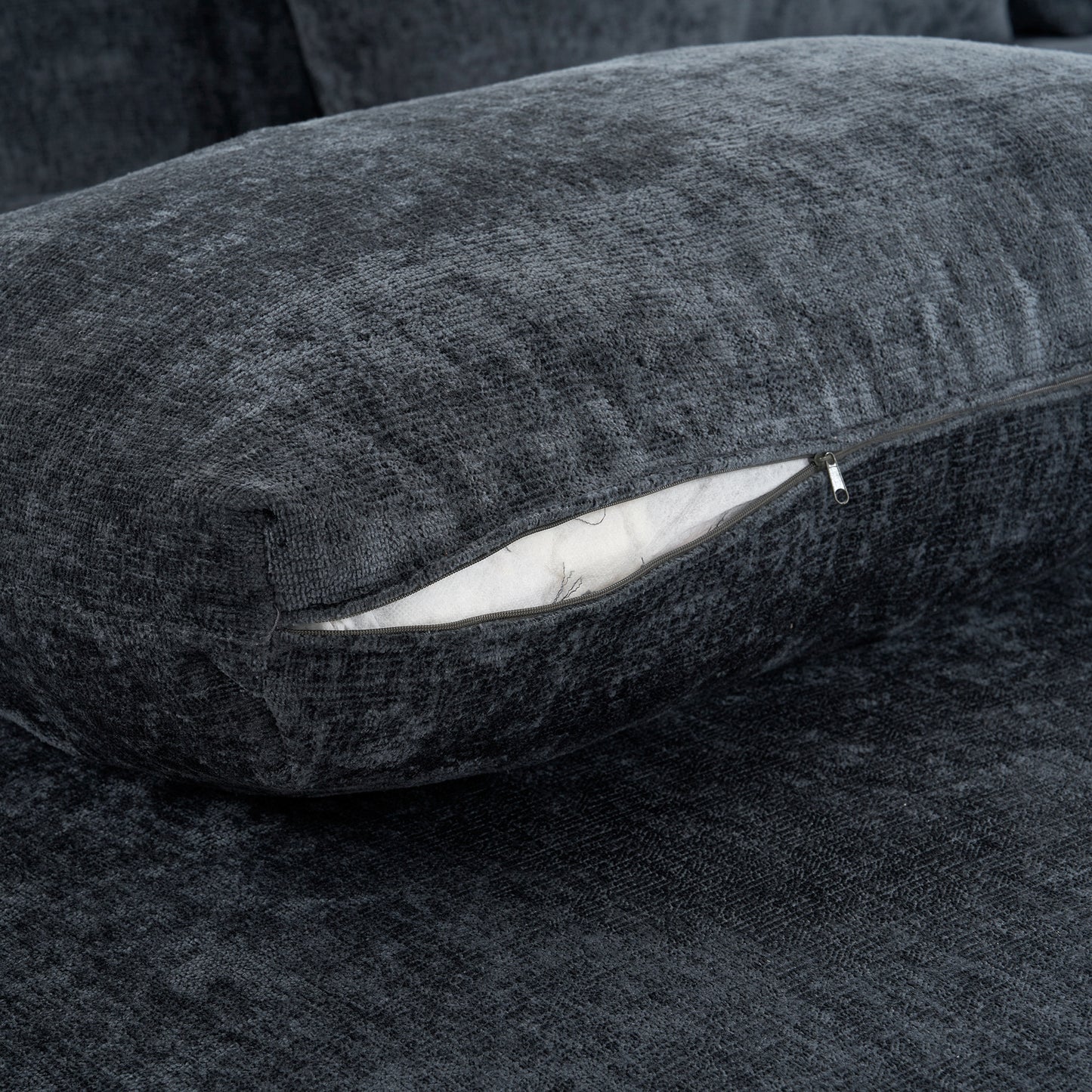 Closeup of dark grey textured sofa fabric with an open zipper revealing white filling