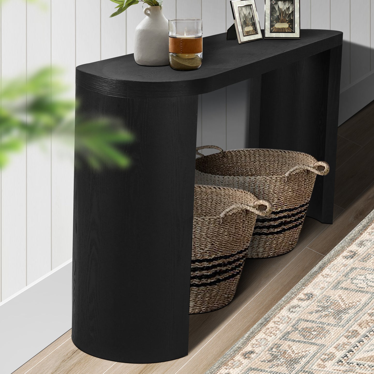 Curved black wood console table with two woven storage baskets underneath