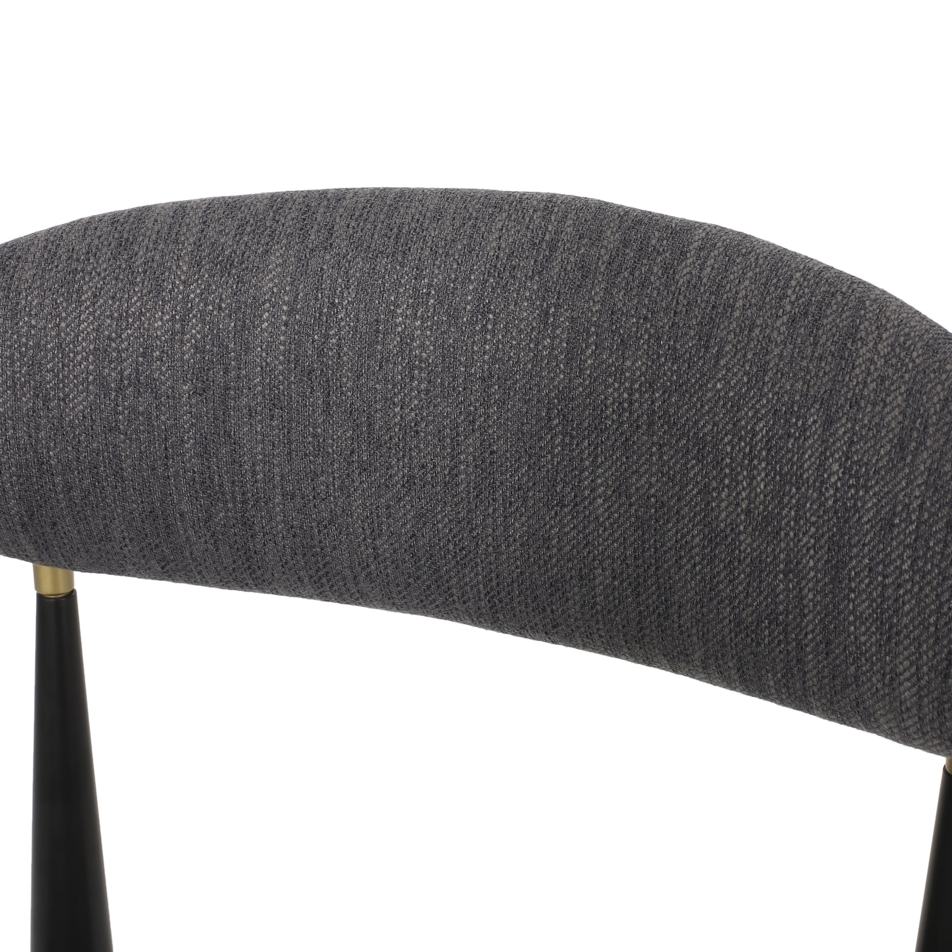 Closeup of curved charcoal grey textured fabric seat back with gold accents and black leg