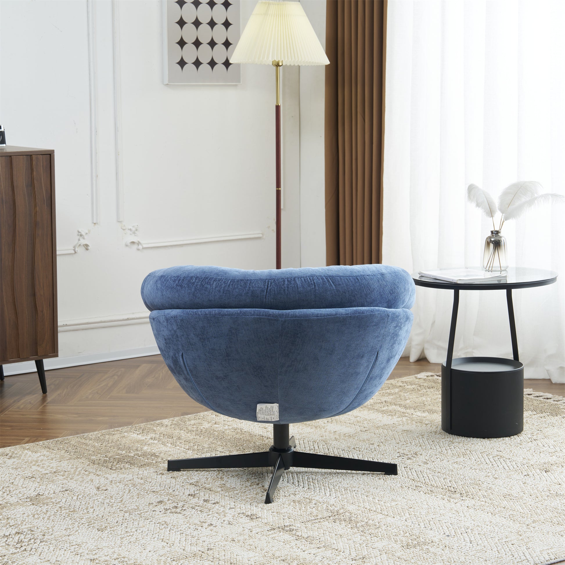 Blue velvet swivel accent chair with black metal base on textured rug
