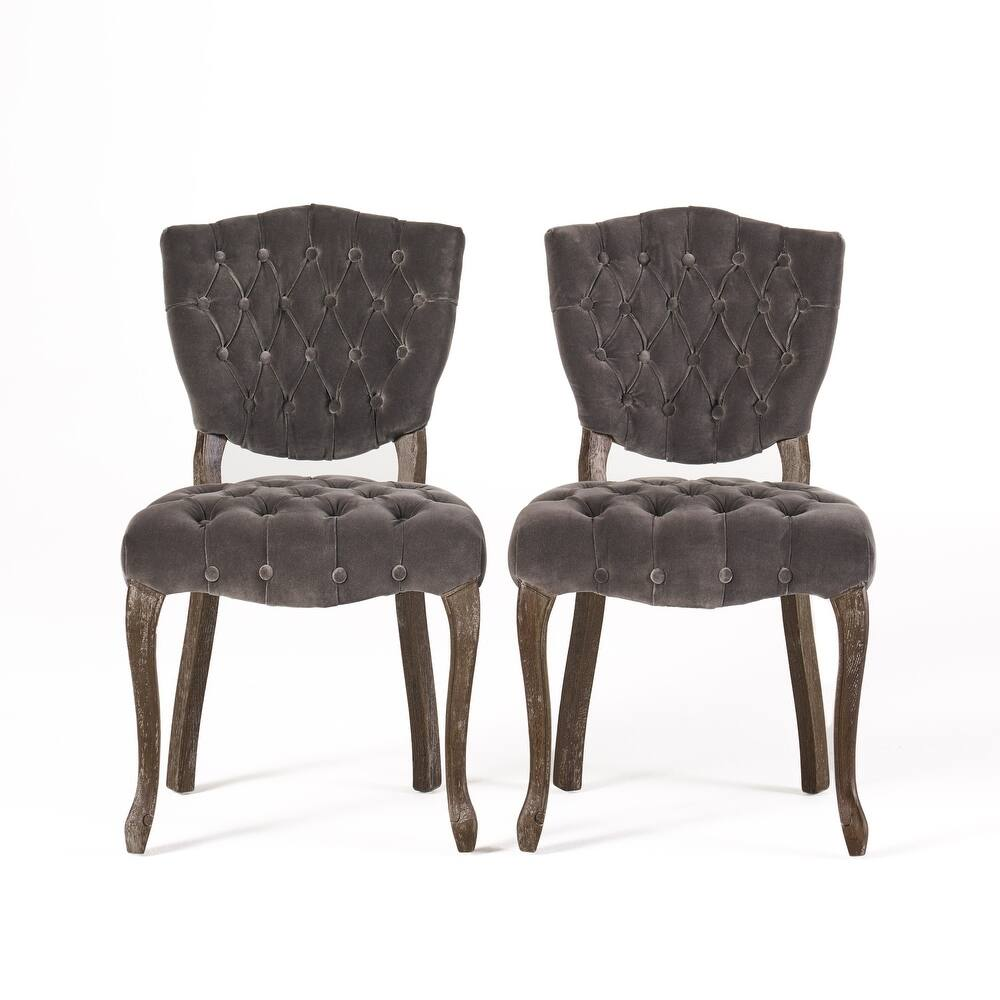 Two grey velvet tufted dining chairs with distressed wooden legs
