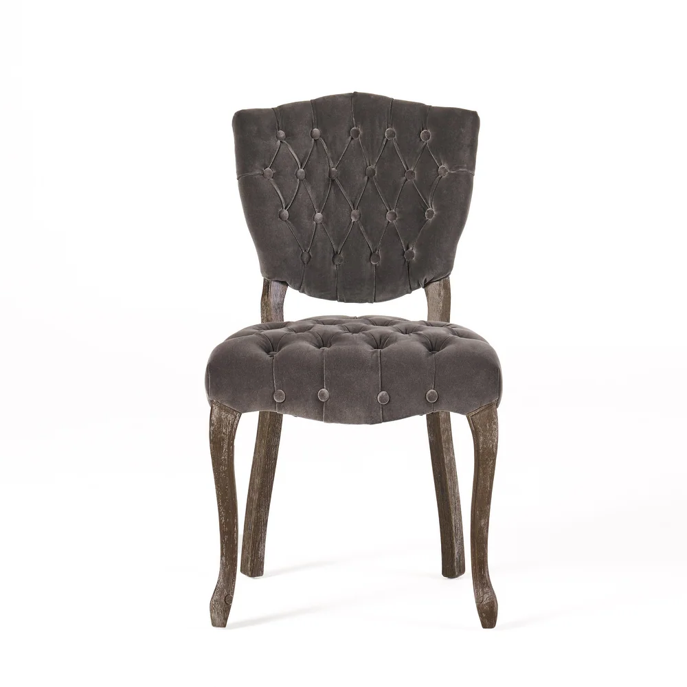 Dark gray velvet dining chair with button tufting and carved wooden legs