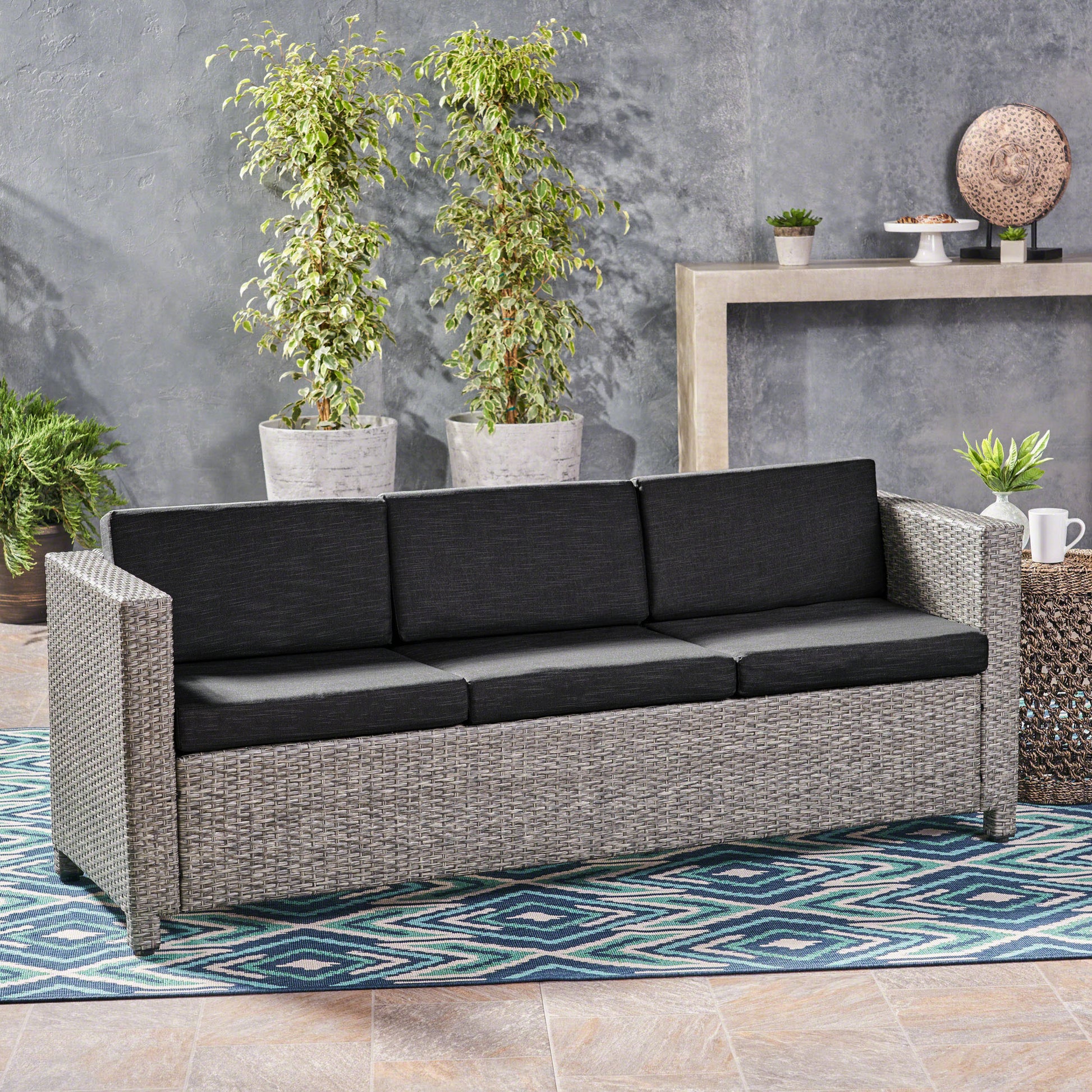 Gray wicker outdoor sofa with plush charcoal cushions
