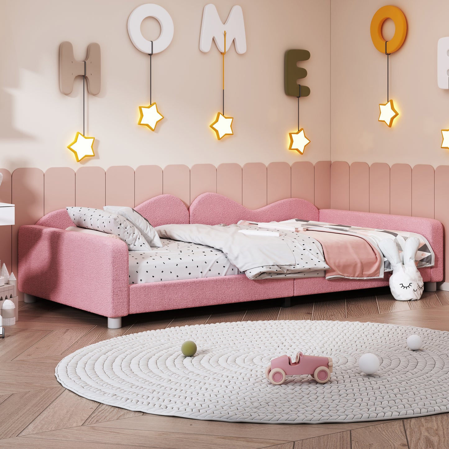 Pink toddler bed with textured fabric and a waveshaped headboard perfect for nursery decor