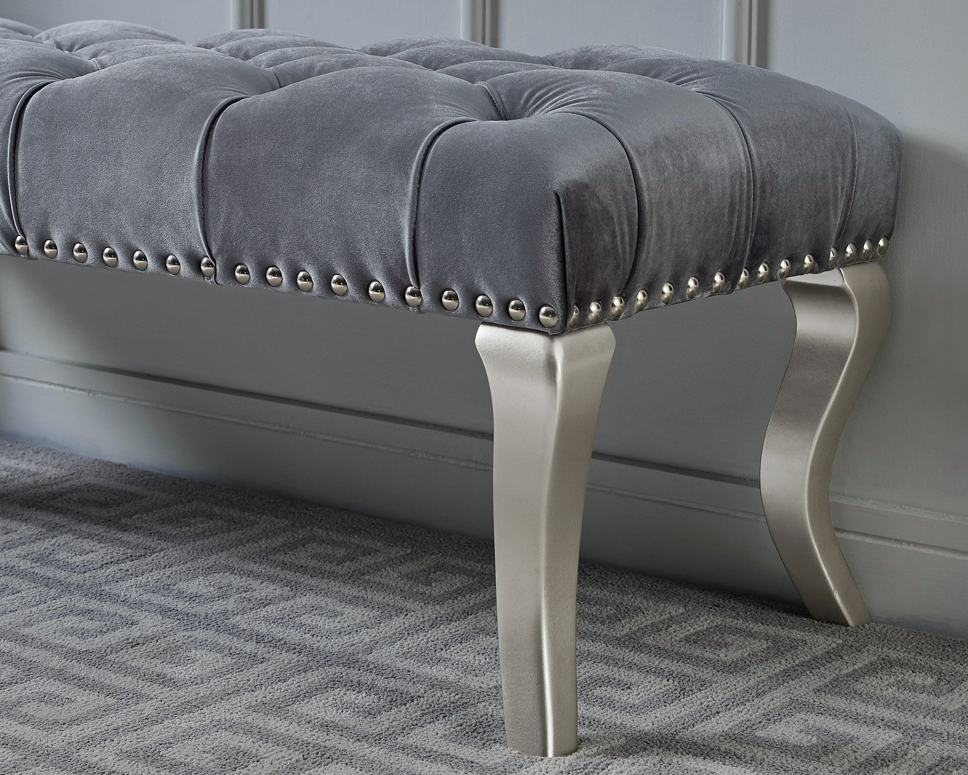 Tufted grey velvet bench with silver nailhead trim and elegant metal legs