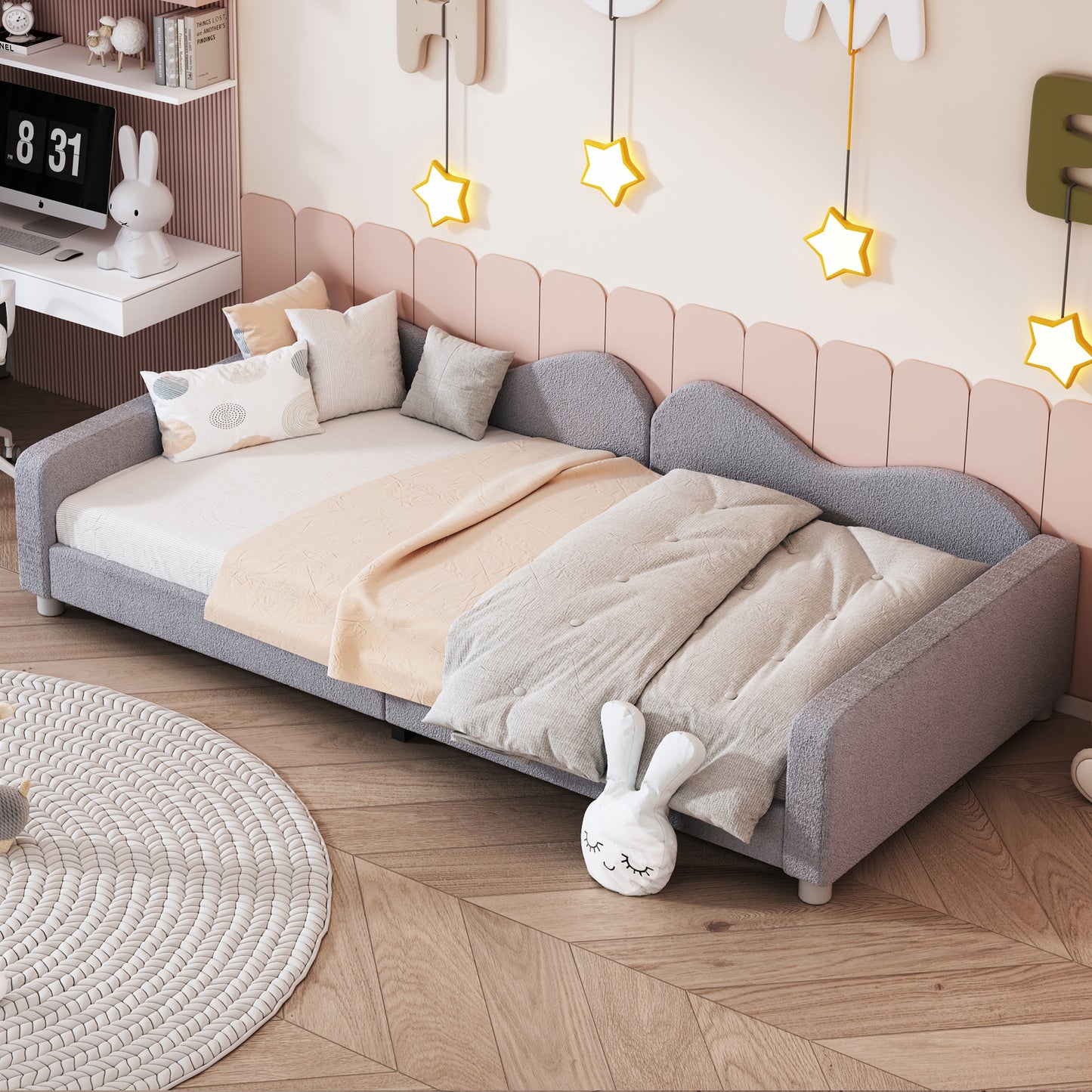 Gray upholstered daybed with patterned pillows and soft blankets