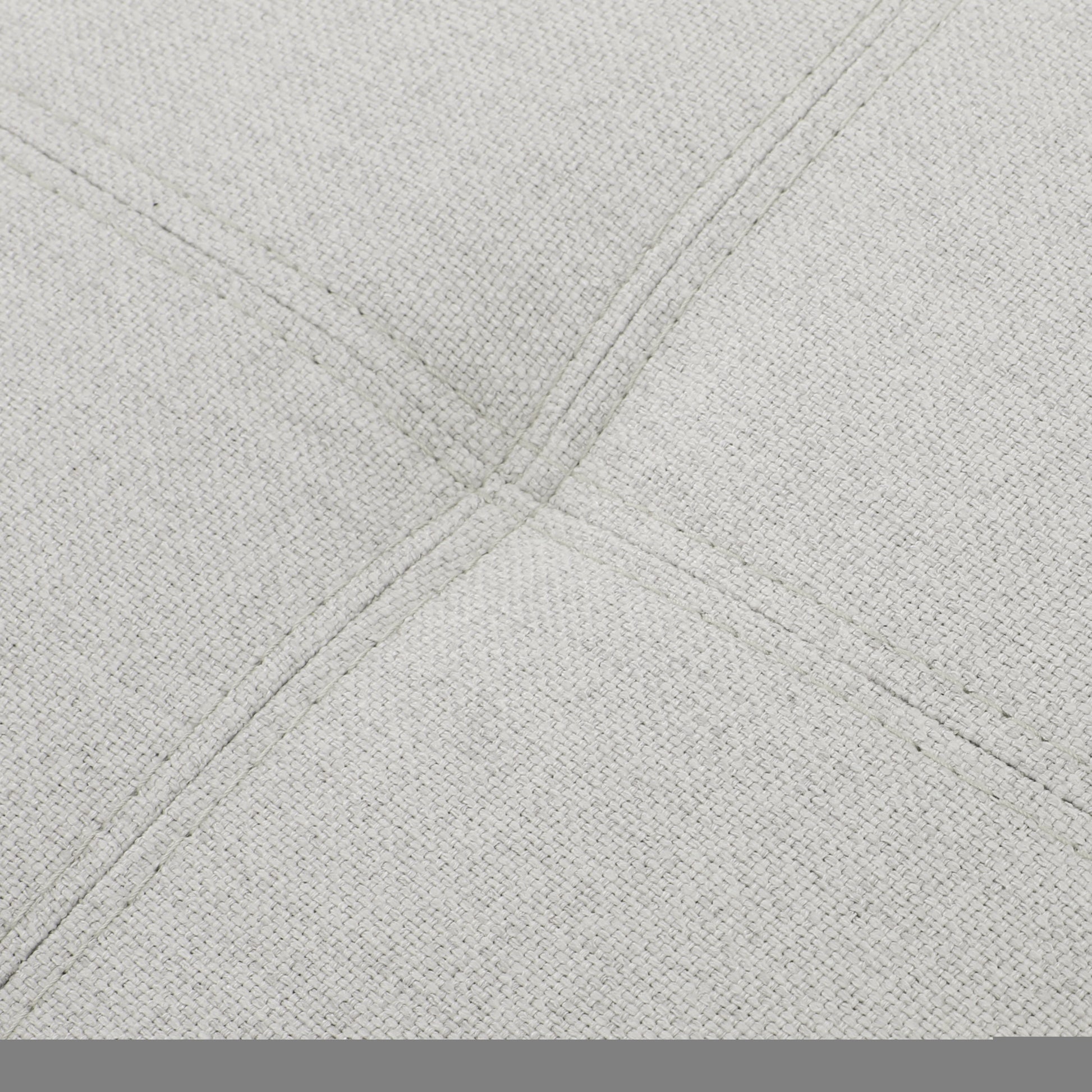 Light grey woven fabric closeup with diamond stitching detail on an accent chair