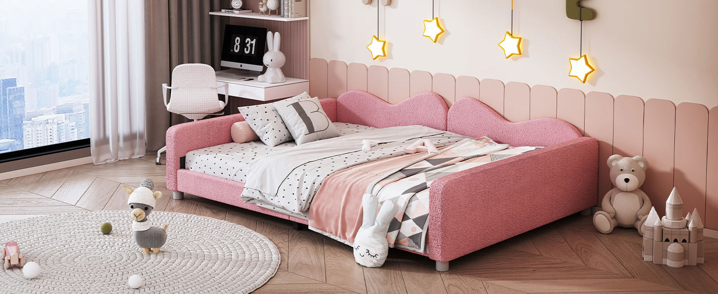Pink upholstered twin daybed with cloudshaped headboard and soft bedding