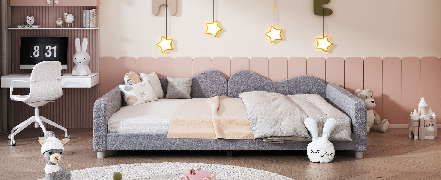 Gray upholstered toddler daybed with plush bedding and playful pillows