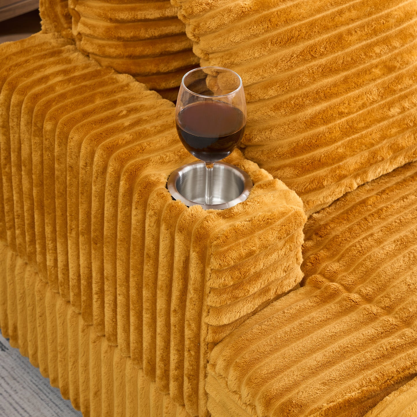 Mustard yellow corduroy sofa armrest with integrated metal cup holder and wine glass