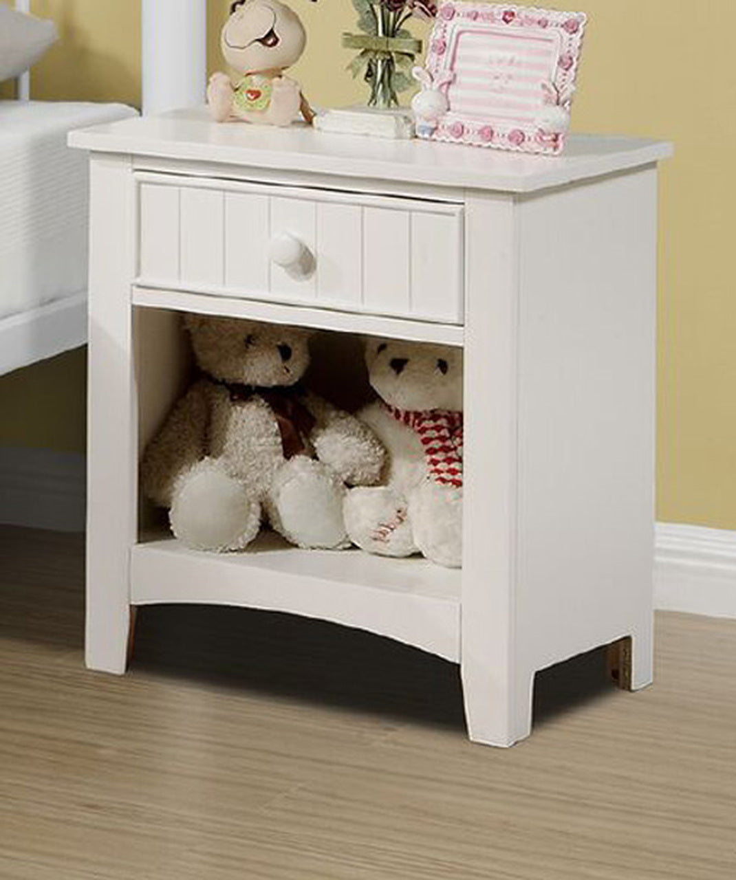 White wooden bedside table with beadboard drawer holding two teddy bears