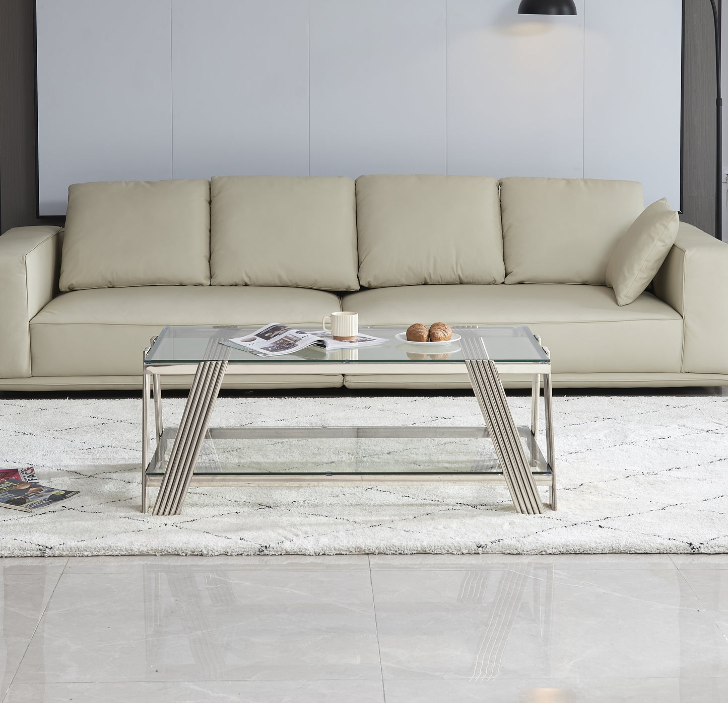 Modern glass coffee table with sleek chrome legs and a lower shelf complementing a neutral living room