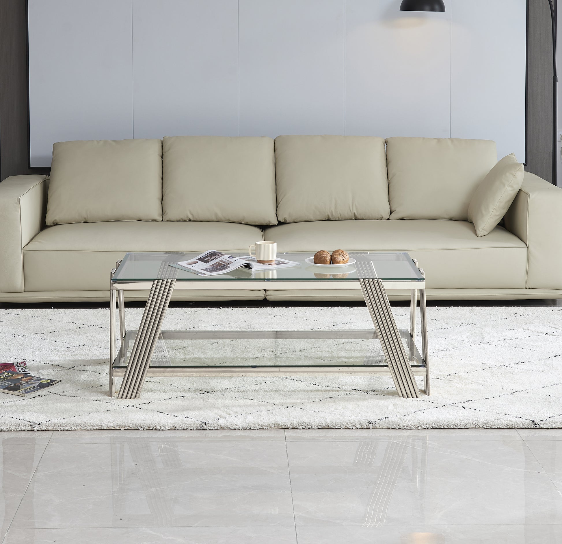Modern glass coffee table with sleek chrome legs and a lower shelf complementing a neutral living room