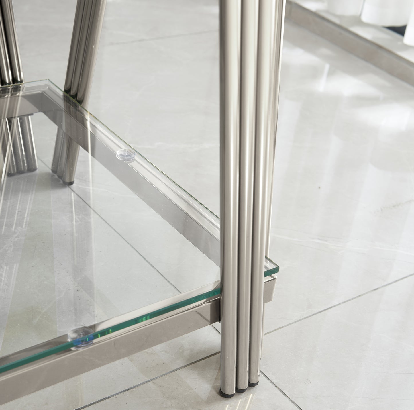 Closeup of silver chrome fluted legs supporting a clear glass table